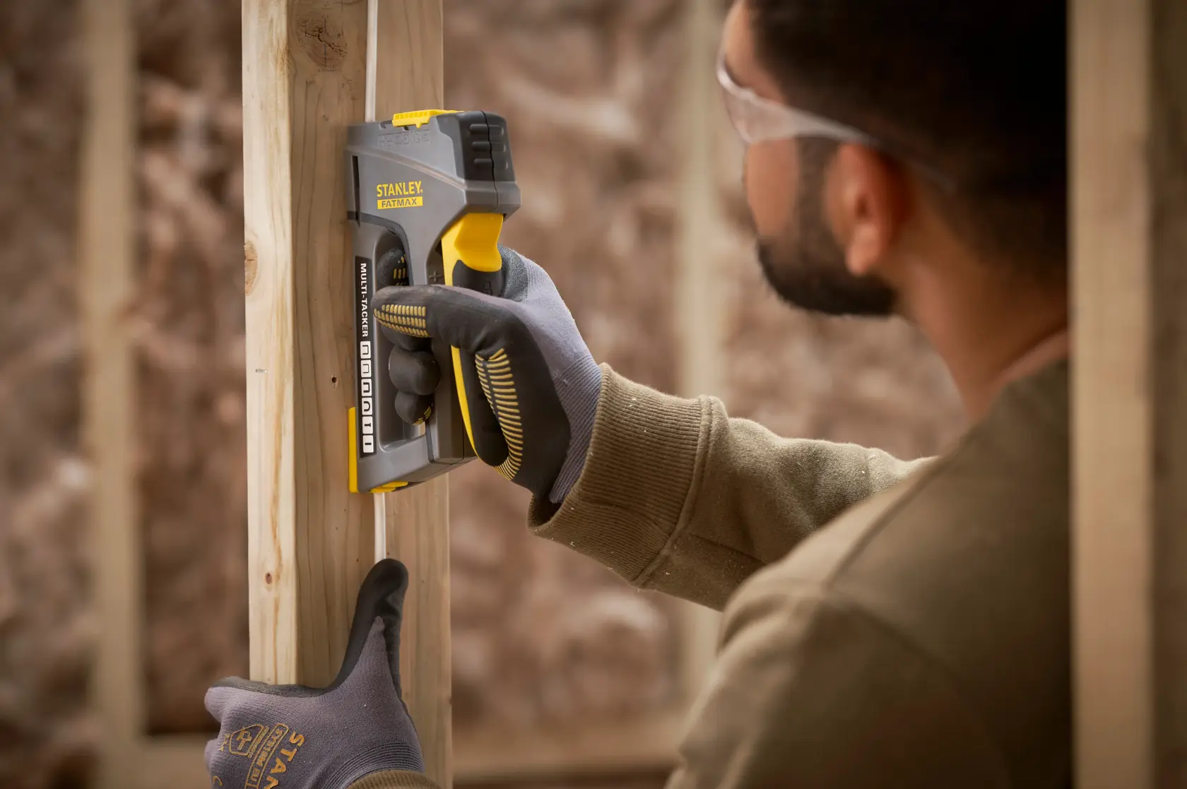 STANLEY FMHT6-70868 graffatrice in uso su telaio di legno, fotografia ravvicinata di attrezzo e guanto.