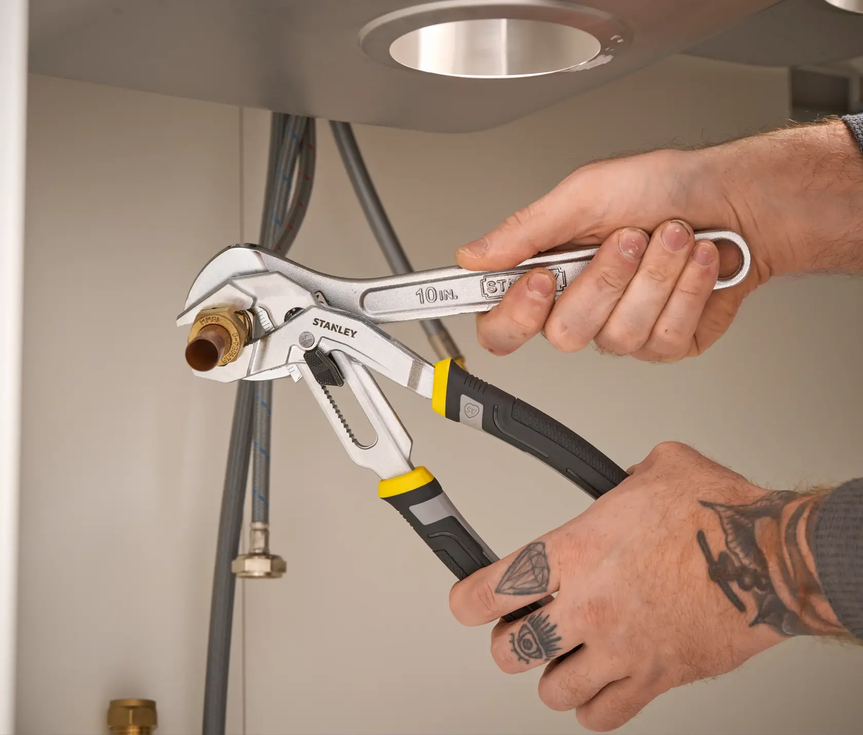 STANLEY FMHT75510-0 pinza regolabile con manici neri e gialli utilizzata su un raccordo sotto un lavandino.