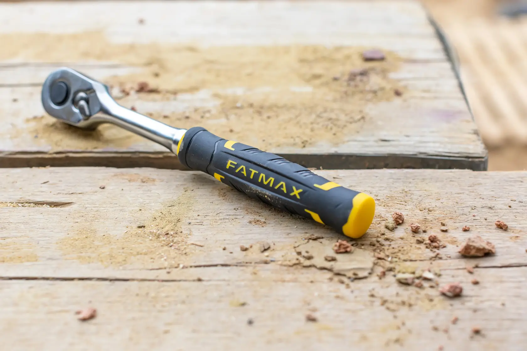 Chiave a cricchetto STANLEY FMMT82684-1 con manico FATMAX nero e giallo su superficie di legno sabbiosa.