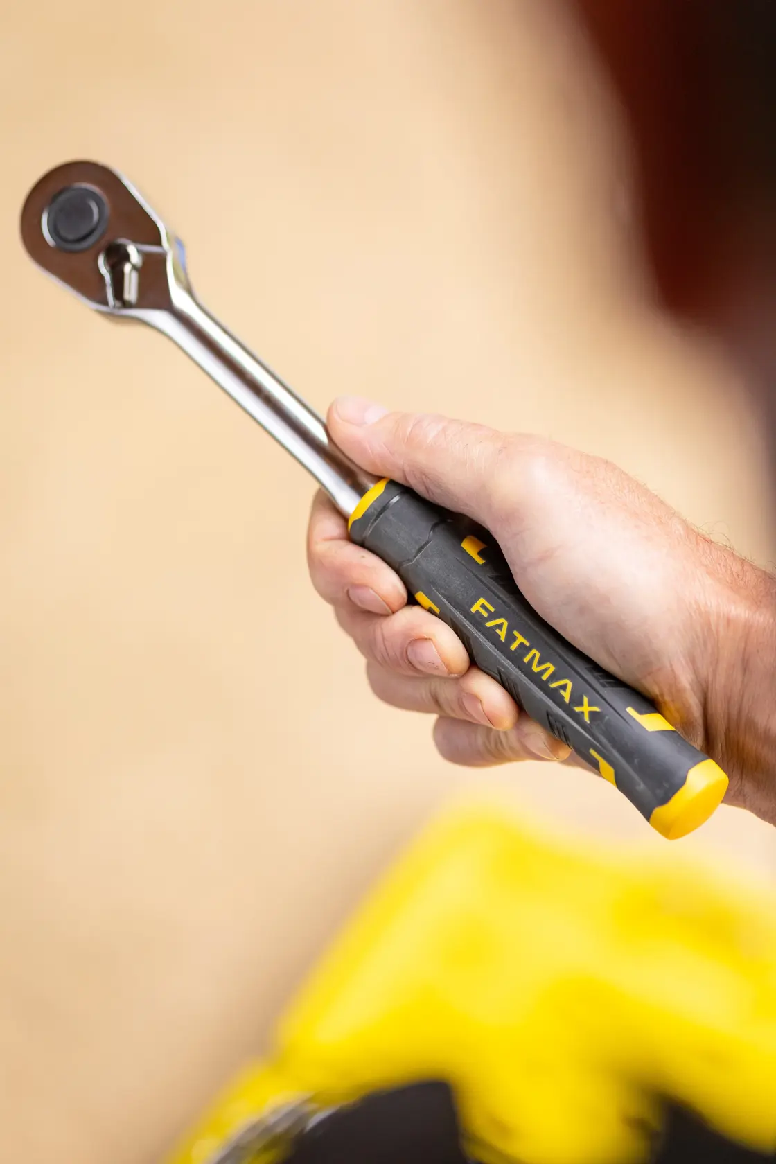Chiave a cricchetto STANLEY FMMT82685-1 con manico FATMAX nero e giallo tenuta in mano, vista laterale.