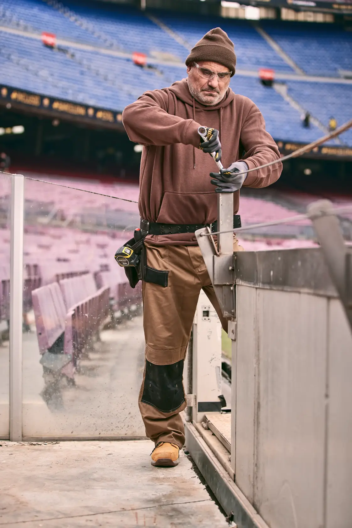 Foto di un operaio con cacciavite STANLEY FMMT82848-0 allo stadio, cintura portautensili e guanti.