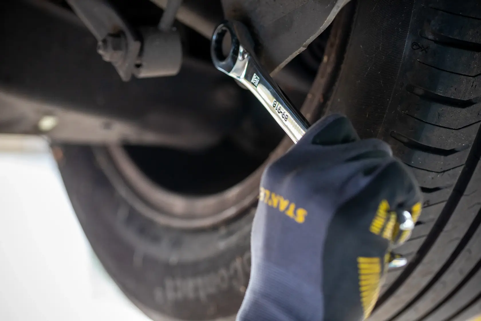 Fotografia di chiave a cricchetto STANLEY FMMT82848-0 usata sulla ruota dell’auto da una mano guantata.
