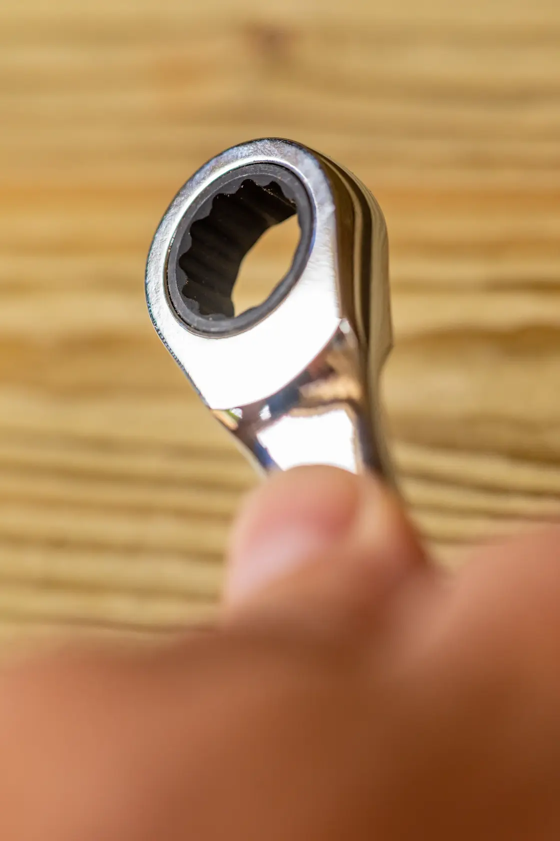 Chiave a cricchetto STANLEY FMMT82849-0 in primo piano in mano, finitura argento, utensile su sfondo in legno.