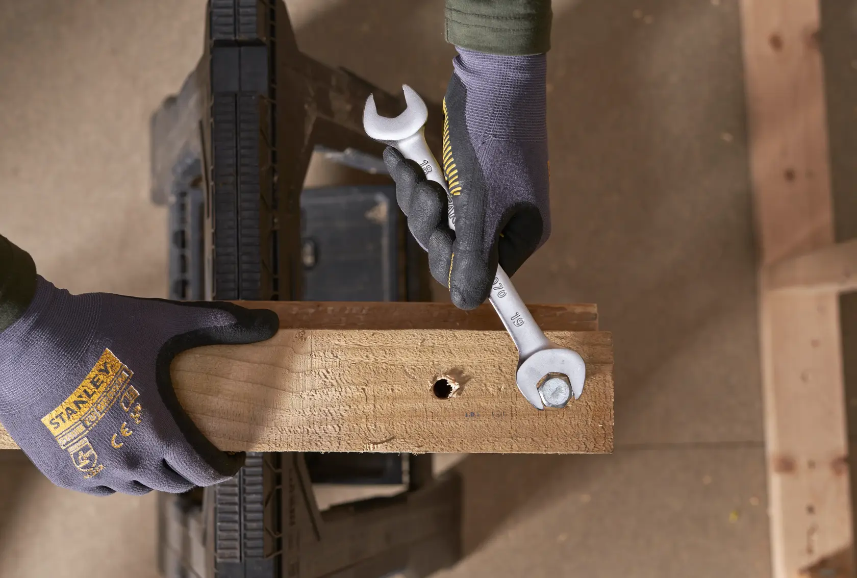 Chiave STANLEY FMMT82902-0 in uso per avvitare un bullone su una tavola di legno, primo piano dall’alto.