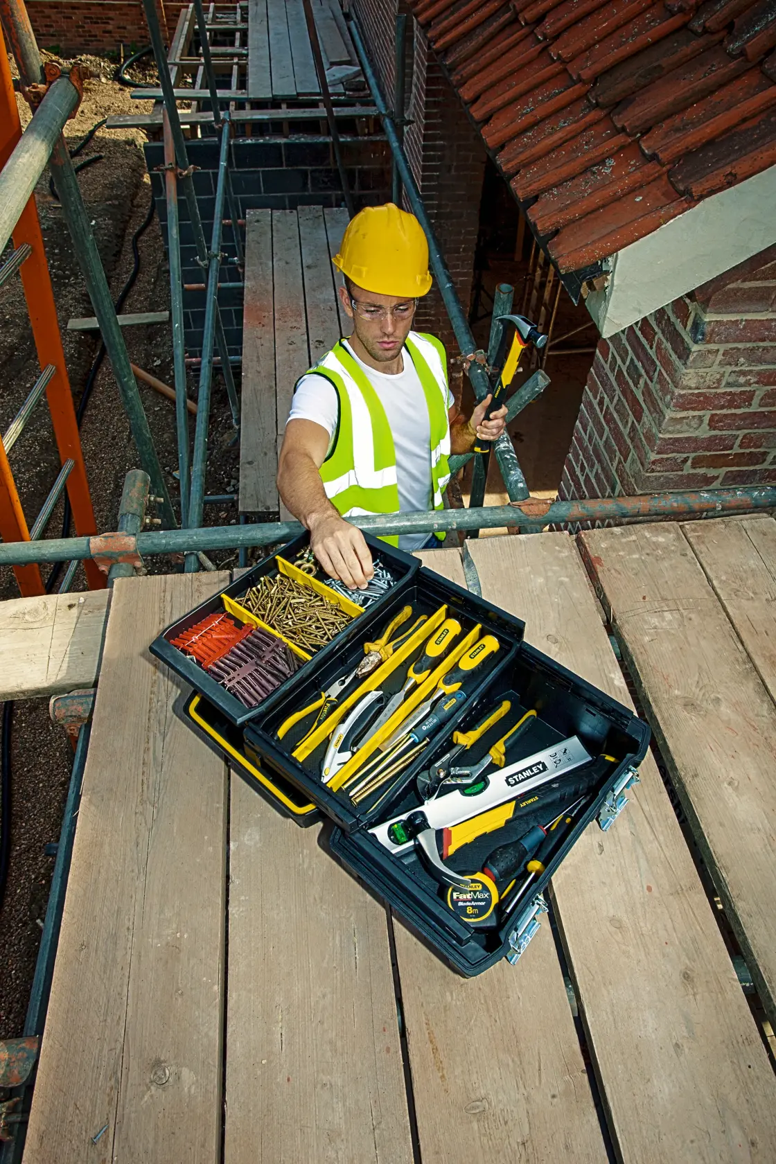 Cassetta degli attrezzi STANLEY FMST1-71219 aperta in cantiere con strumenti manuali e fissaggi assortiti.