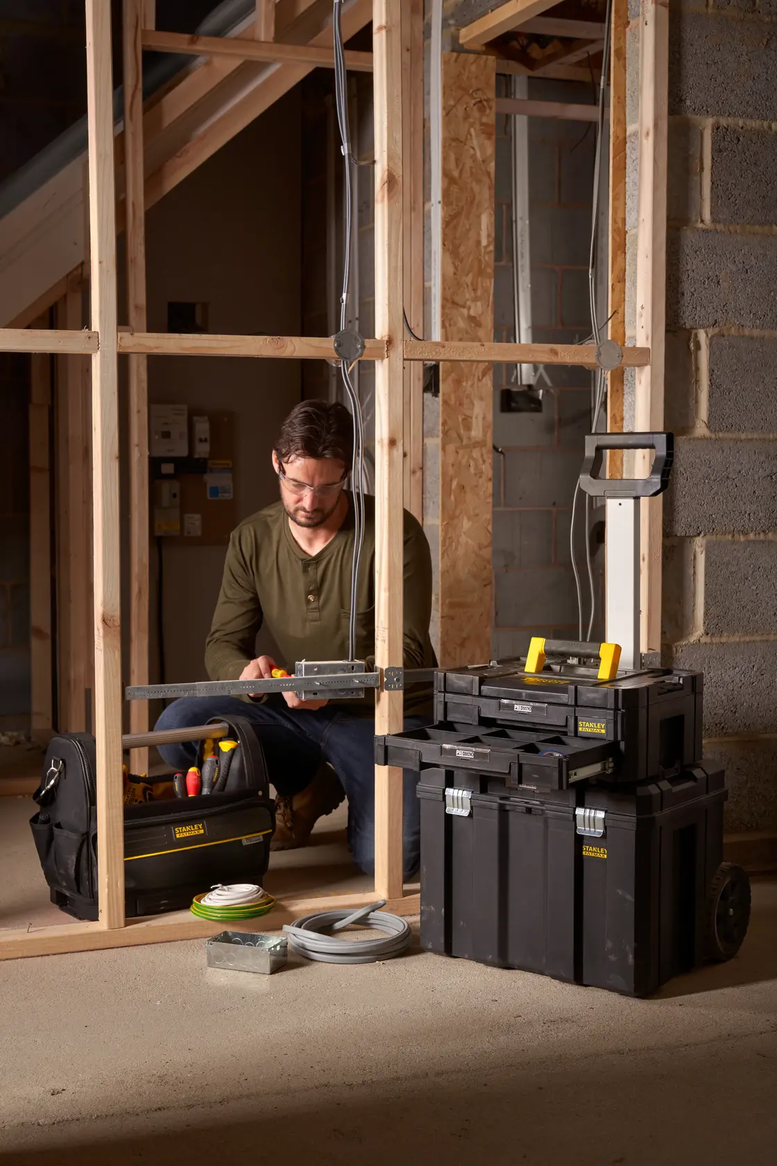 STANLEY FMST1-75753 cassetta degli attrezzi nera con ruote e organizer usati in un cantiere con un operaio.