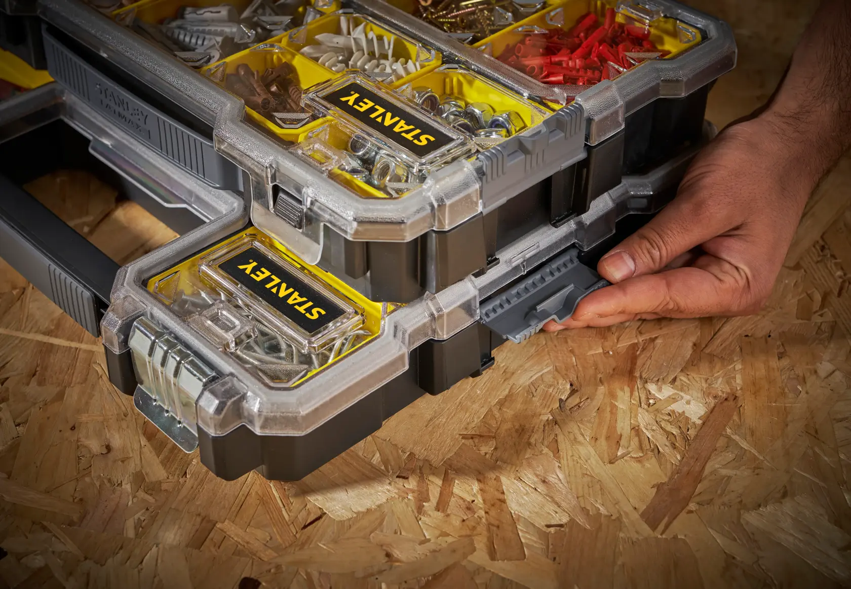 STANLEY FMST1-75779 organizer impilabile con scomparti gialli, mano sulla chiusura laterale, vista angolata.