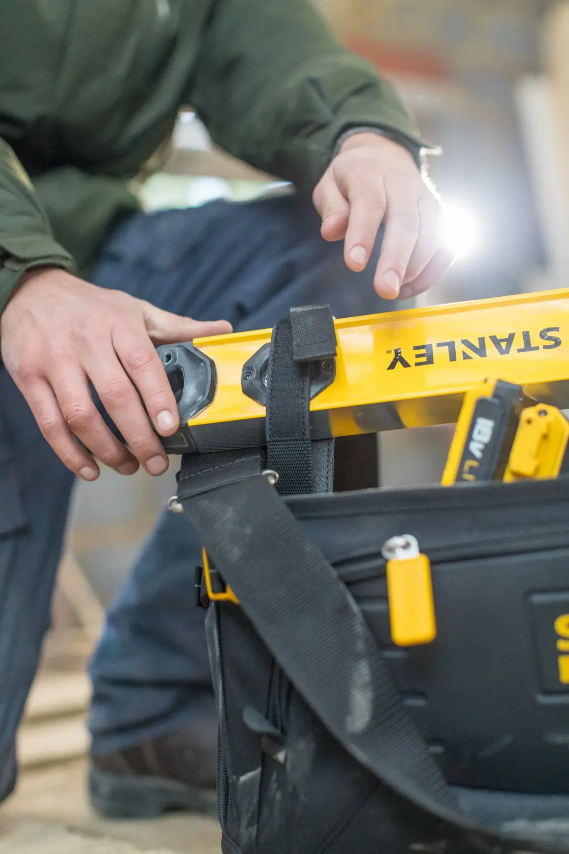 Borsa porta attrezzi STANLEY FMST1-80146 con strumenti e livella gialla, primo piano, fotografia in cantiere.