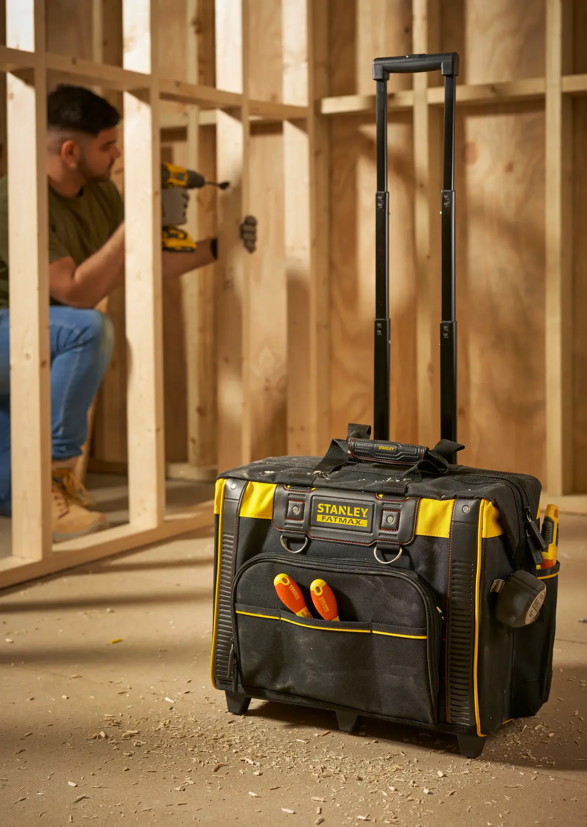 STANLEY FMST1-80148 borsa porta attrezzi su ruote con manico, nera e gialla, in cantiere, vista frontale.