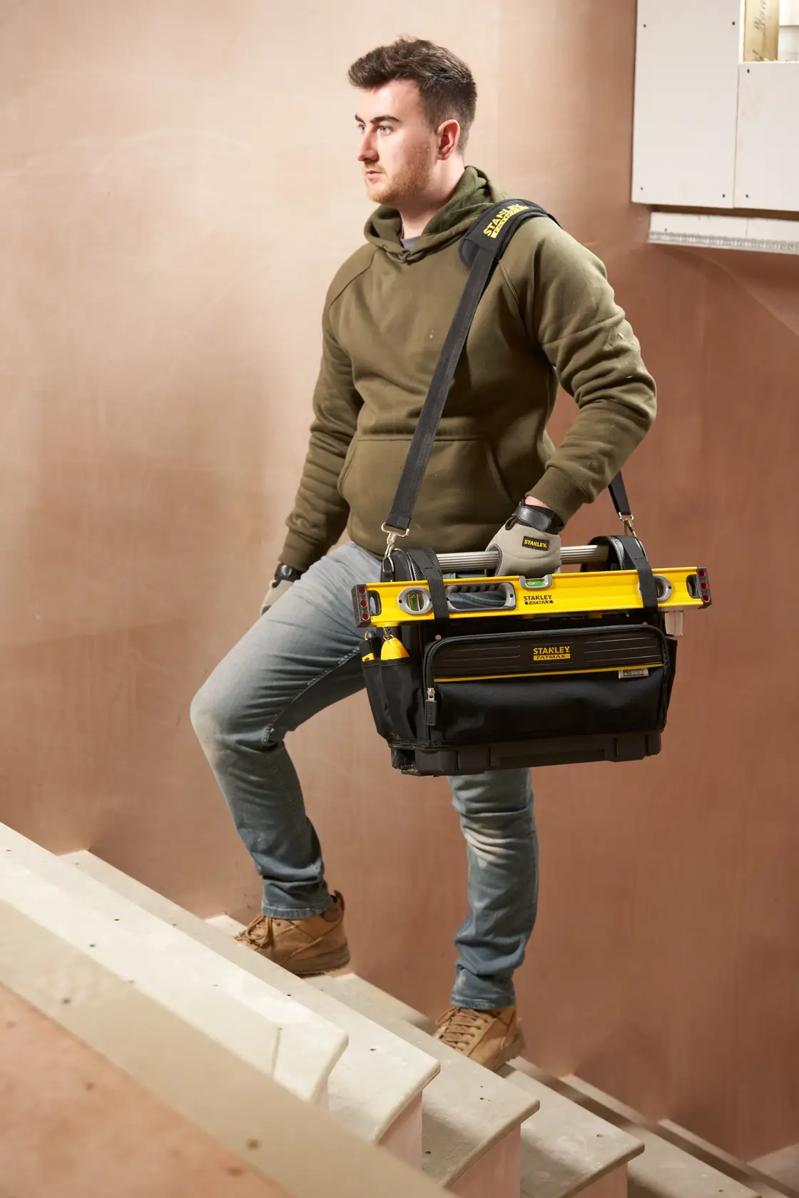 STANLEY FMST17626-1 borsa porta attrezzi con attrezzi, portata da una persona sulle scale, foto frontale.