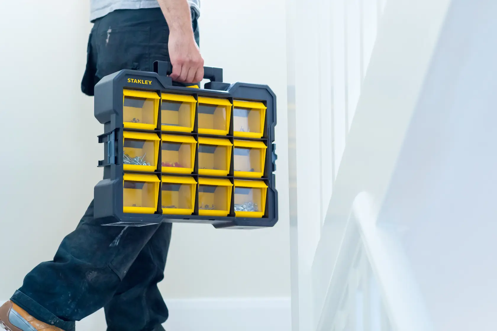 Organizer STANLEY FMST81077-1 con scomparti gialli trasparenti, portato a mano in ambienti interni.