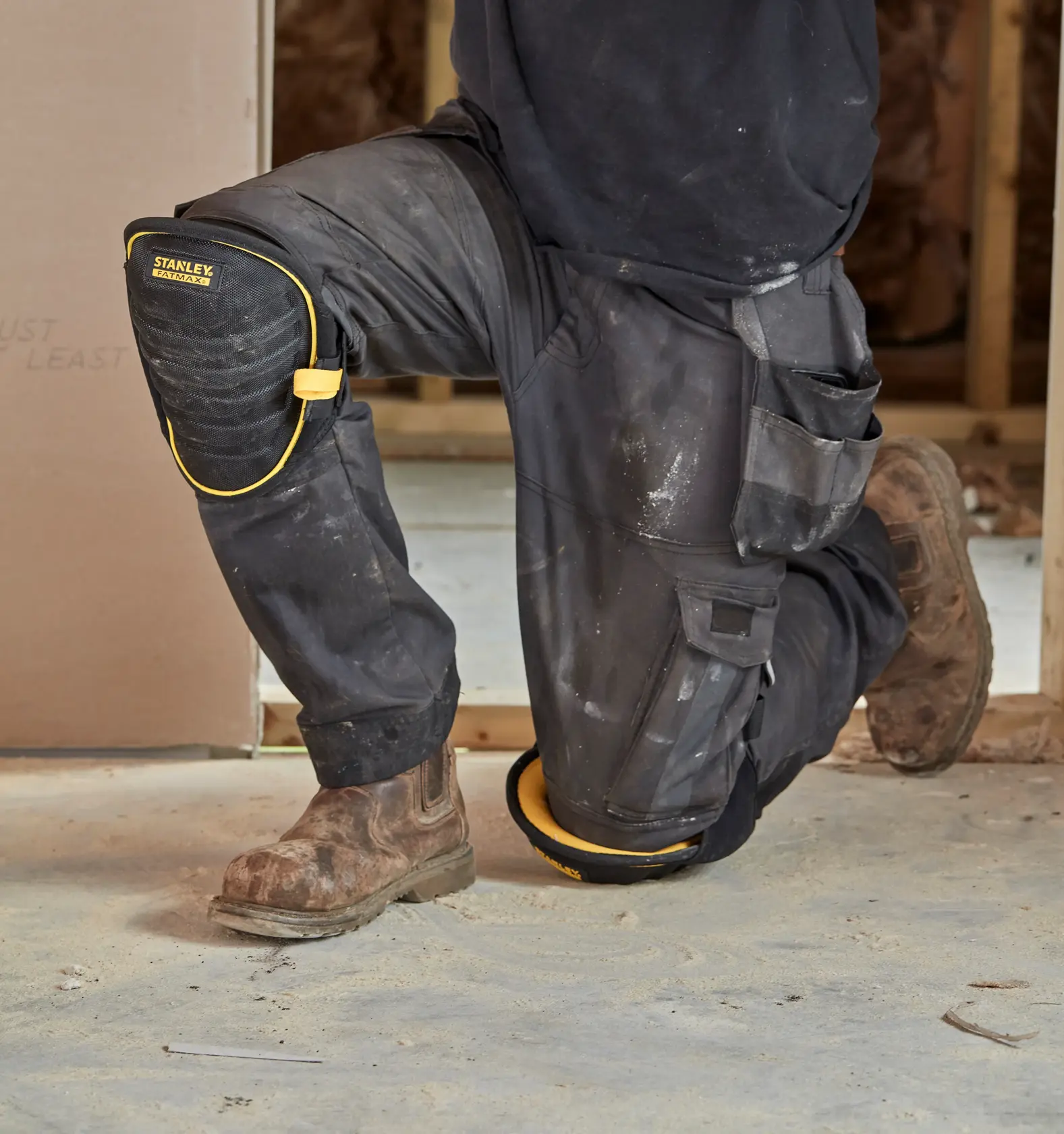 Ginocchiera nera e gialla STANLEY FMST82959-1 indossata da una persona inginocchiata in un cantiere.