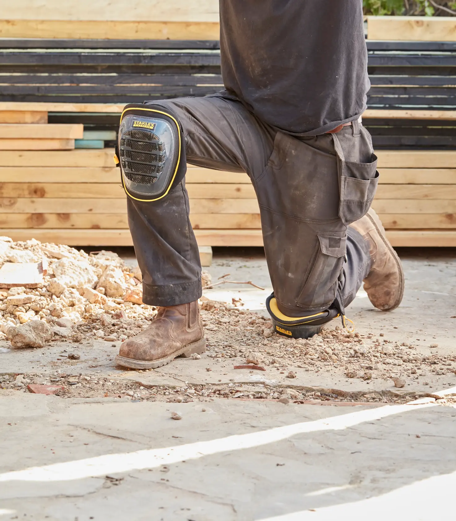 Ginocchiere da lavoro STANLEY FMST82960-1 indossate in cantiere, nere con bordo giallo e guscio resistente.
