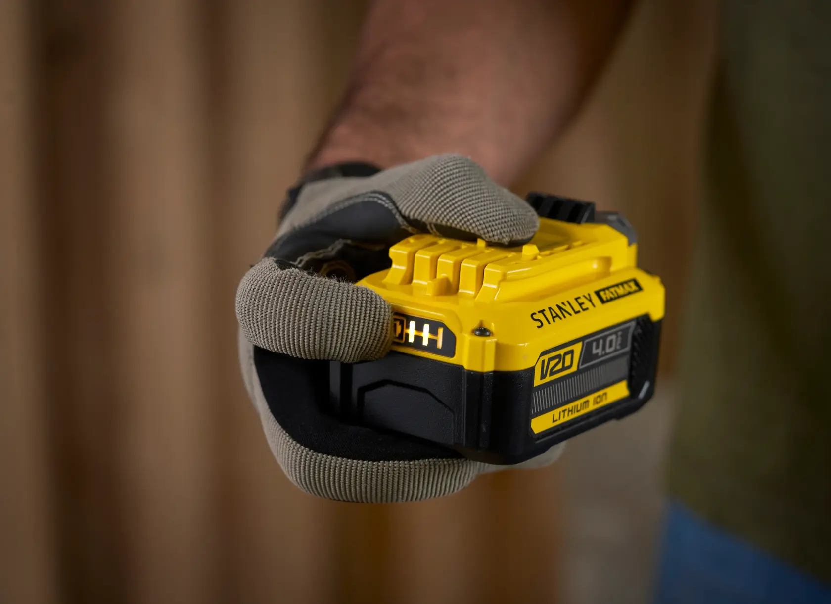 Foto della batteria agli ioni di litio STANLEY SFMCB14M1 V20 4,0Ah tenuta in una mano con guanto.