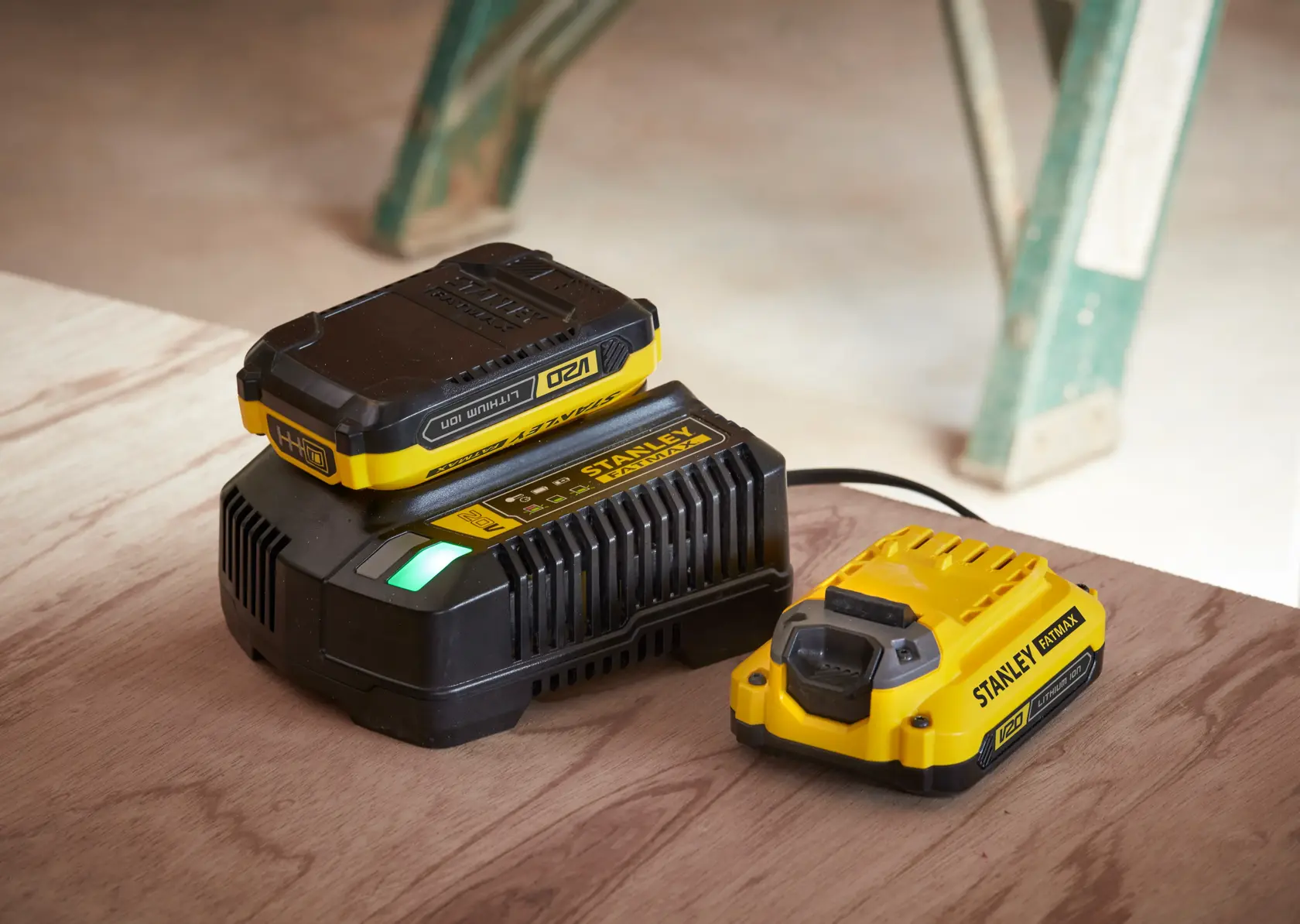 STANLEY SFMCB14 caricabatterie e batteria, giallo e nero, angolo laterale su superficie in legno.