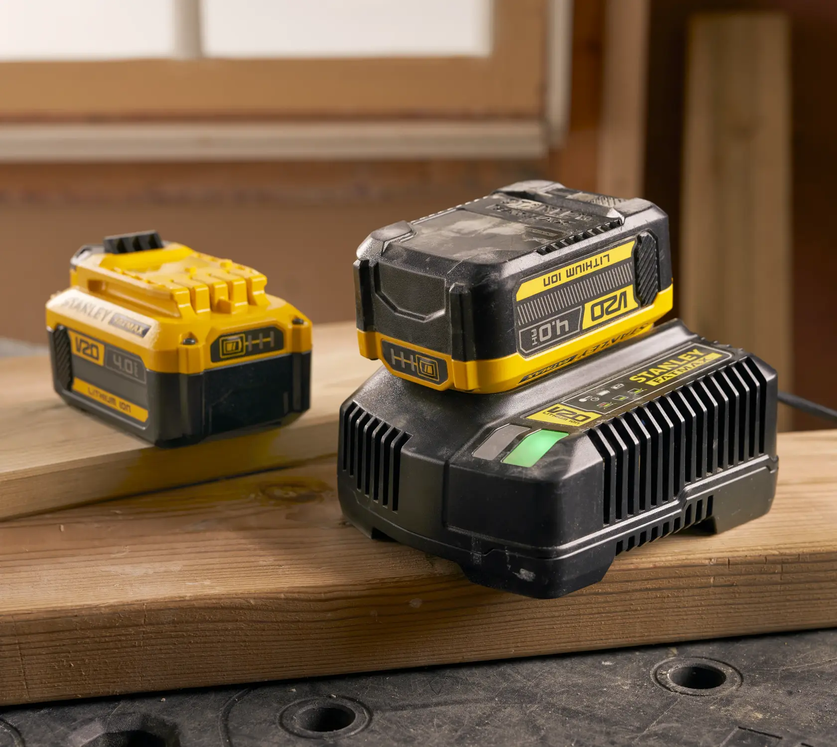 Foto di batteria STANLEY SFMCB204 V20 4.0Ah agli ioni di litio e caricabatterie, giallo e nero su assi di legno.