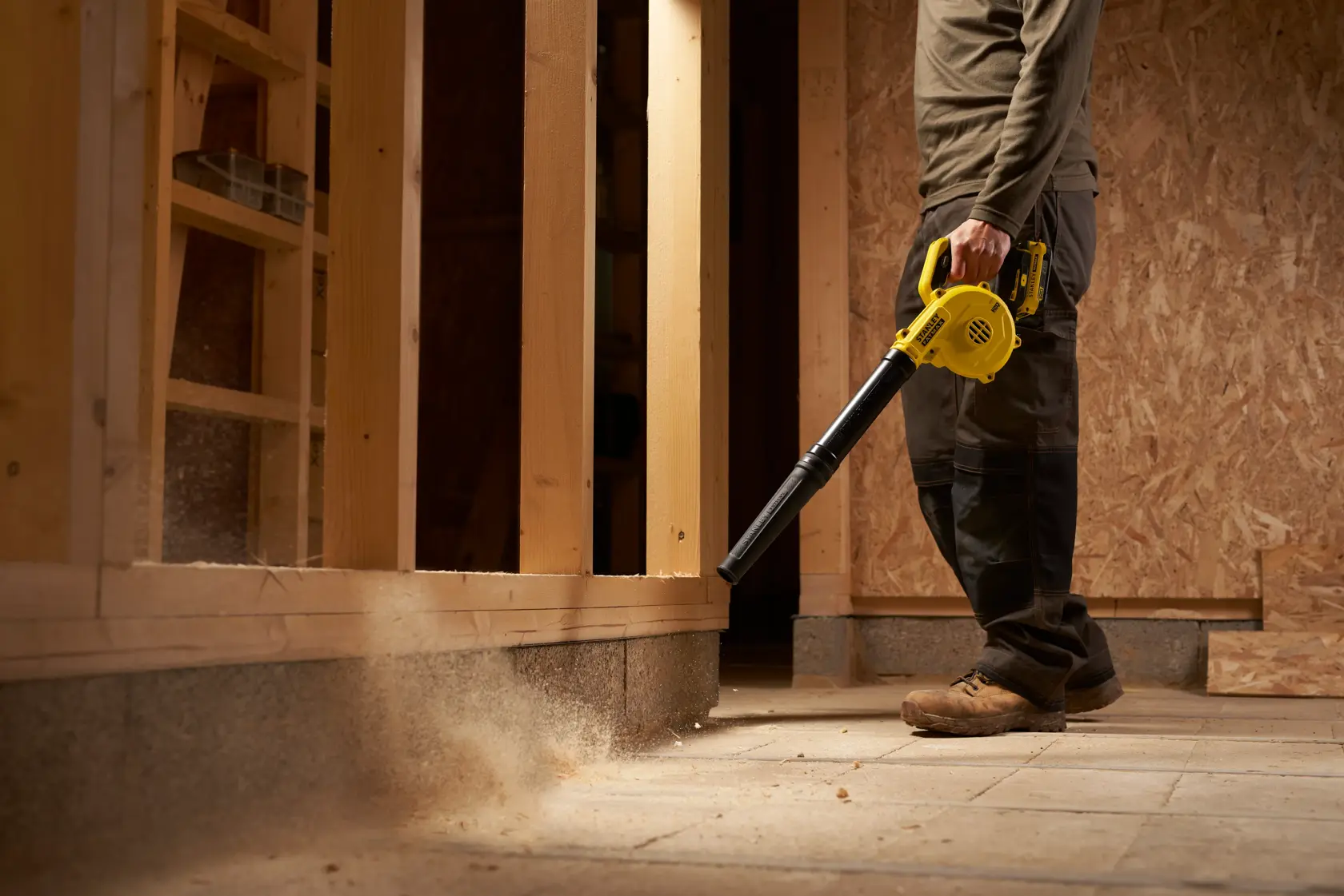 STANLEY SFMCBL01B soffiatore in uso in cantiere, utensile giallo senza fili pulisce la polvere dal pavimento.