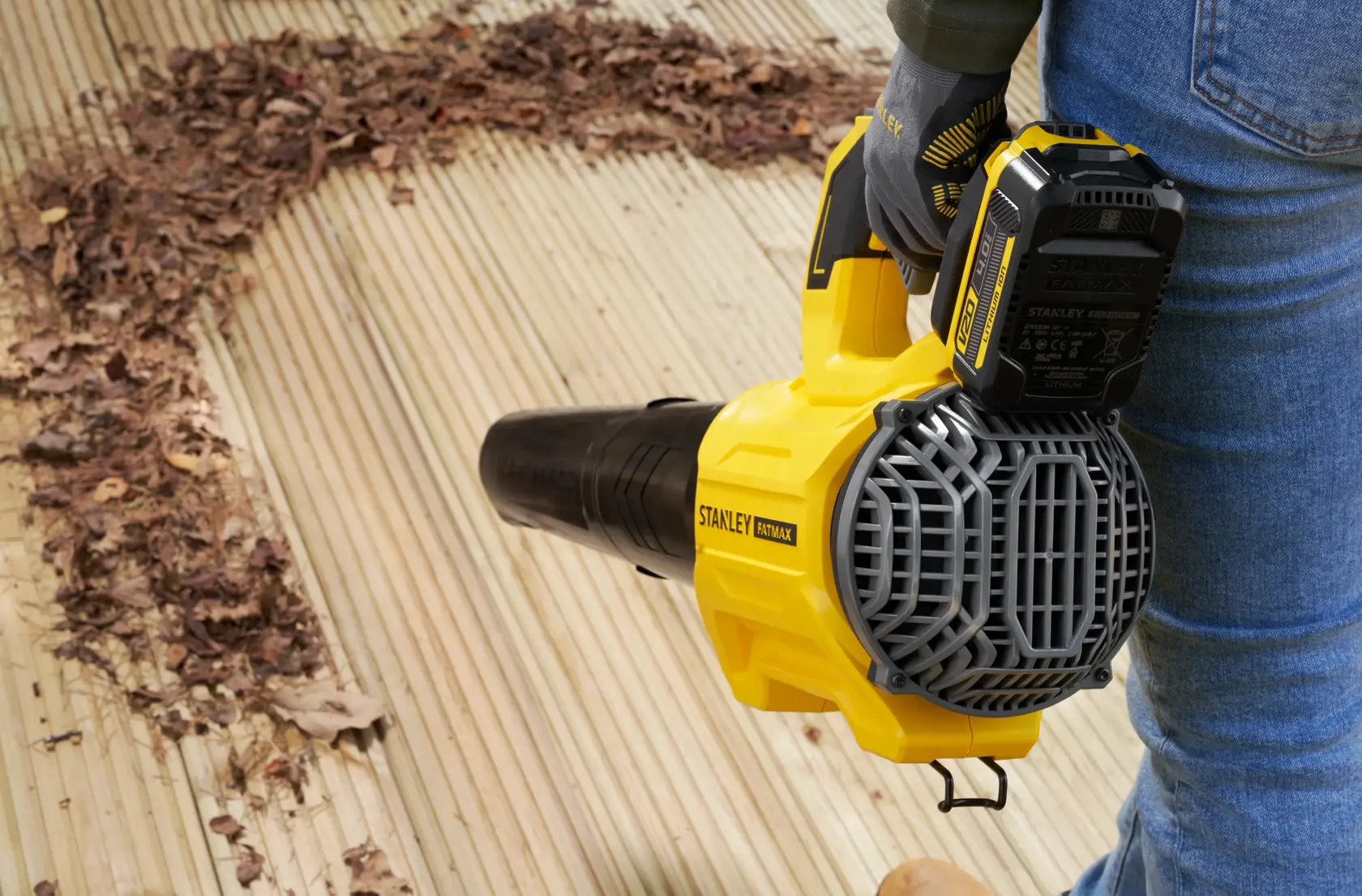 STANLEY SFMCBL730B soffiatore per foglie in uso su terrazza in legno, rimuove foglie secche, vista laterale.
