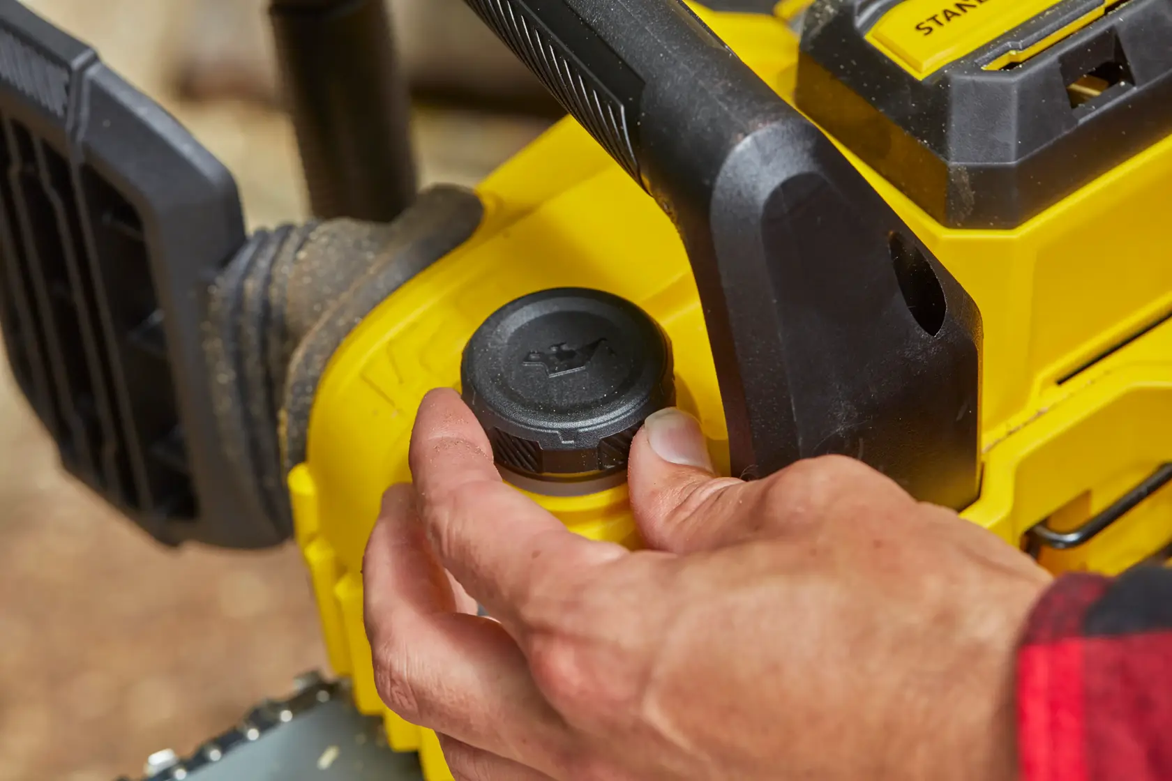 STANLEY SFMCCS630M1 motosega dettaglio, mano regola tappo dell'olio, design giallo e nero, ambiente esterno.