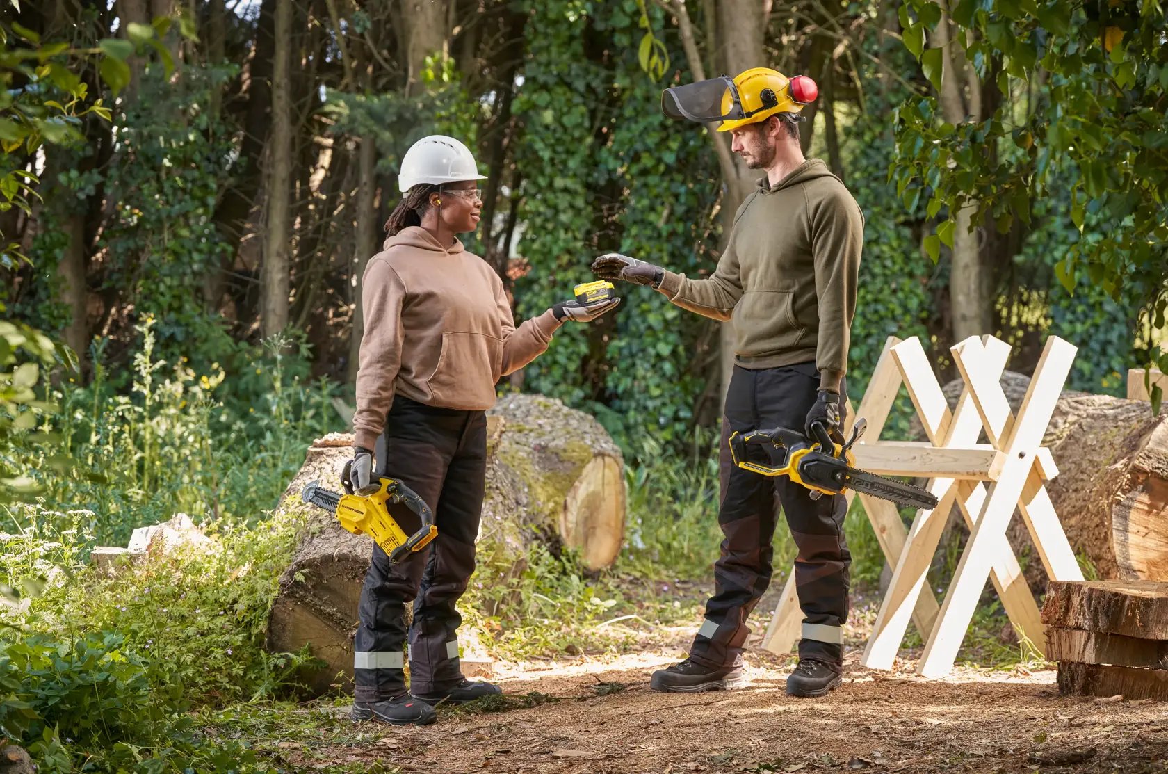STANLEY SFMCCS730B motosega tenuta da due persone all'aperto con equipaggiamento di sicurezza vicino a tronchi e cavalletto.