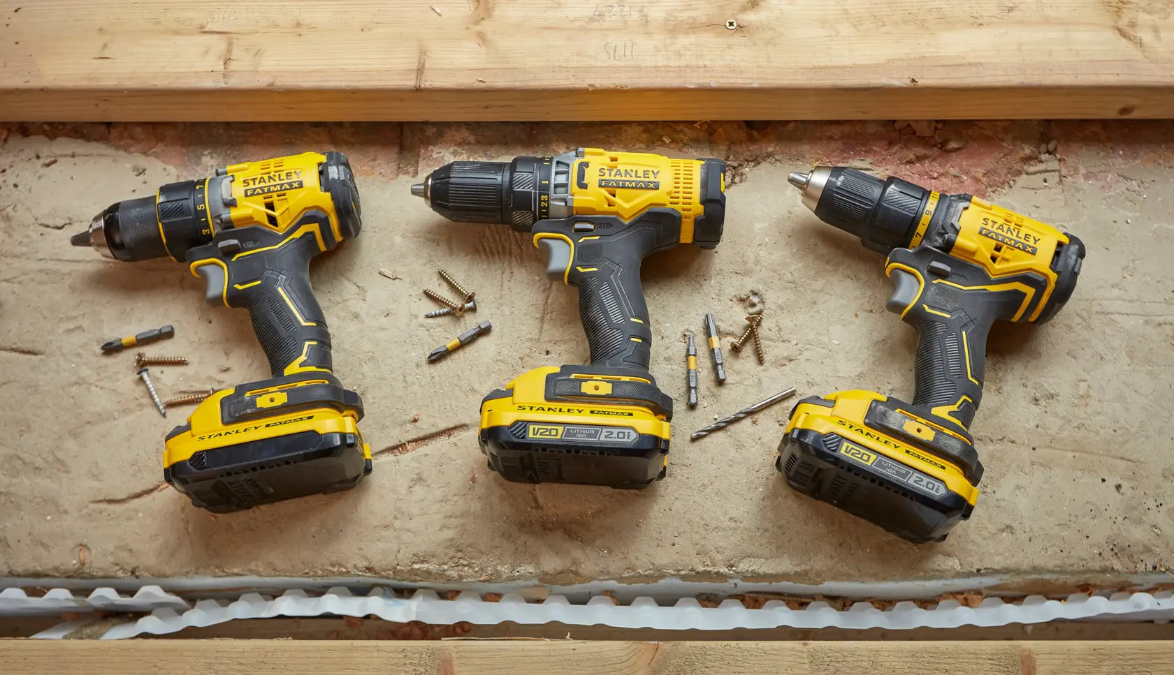 Trapani cordless STANLEY SFMCD720B giallo e nero, vista dall'alto su cemento con punte e viti.