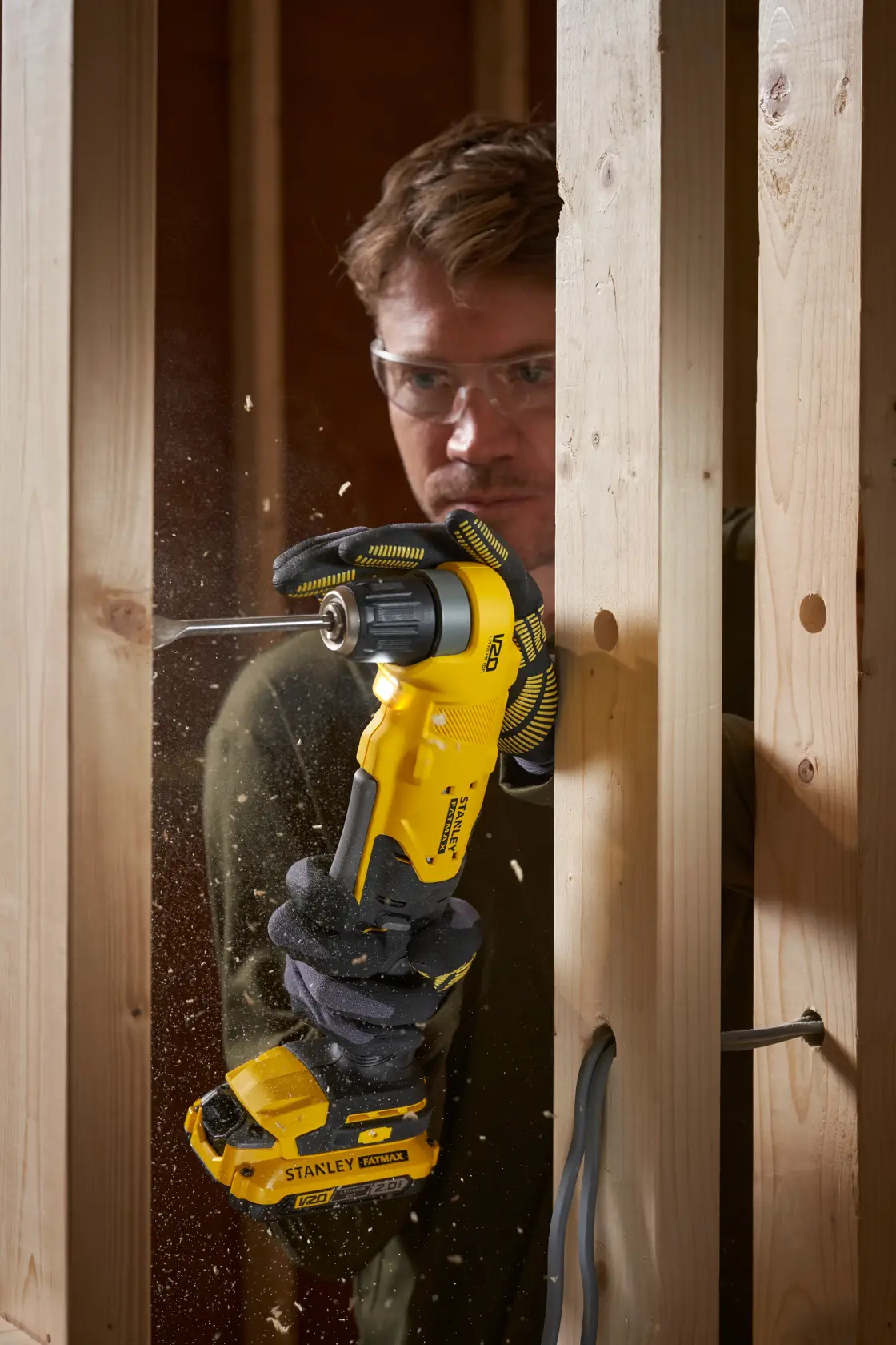 STANLEY SFMCD750B trapano angolare a batteria in uso per forare montanti in legno, primo piano in azione.