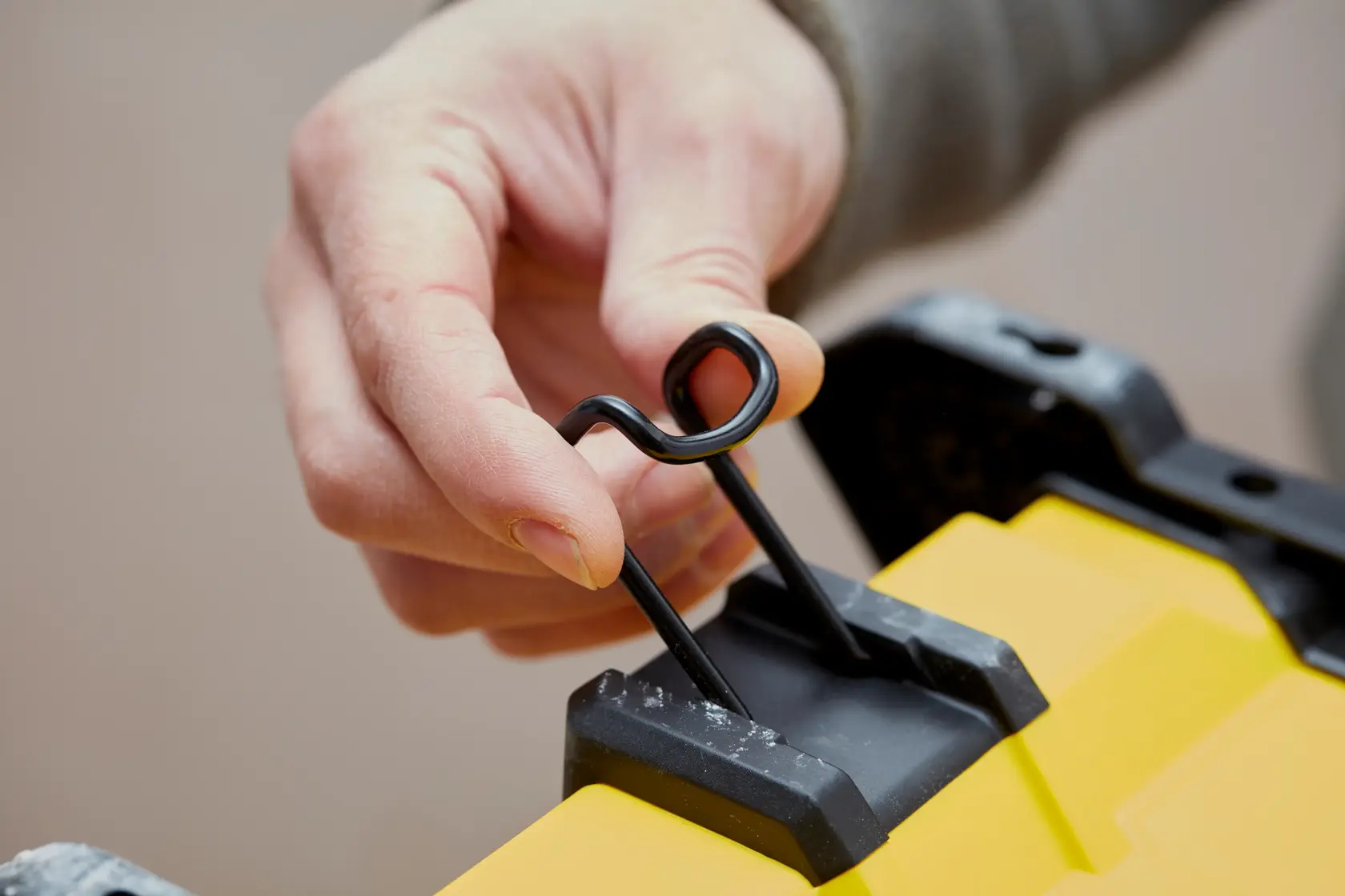 STANLEY SFMCE001B primo piano di mano che usa una chiusura metallica nera su superficie gialla del prodotto.