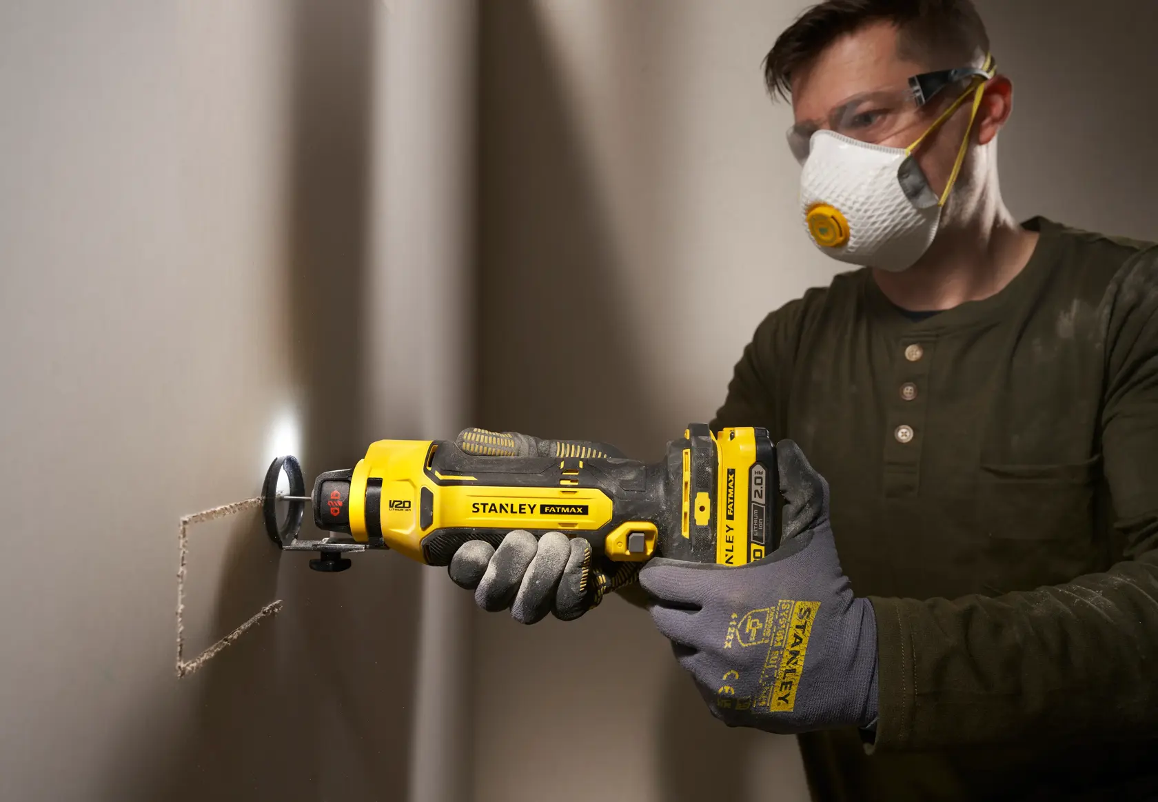 Foto dell’utensile rotativo STANLEY SFMCE200B che taglia cartongesso, tenuto da mani guantate, in cantiere.