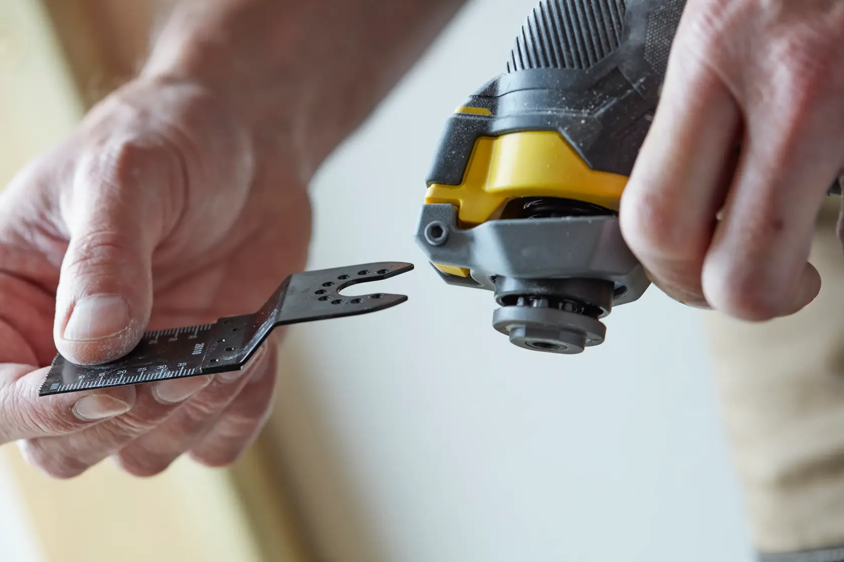 STANLEY SFMCE500B utensile multifunzione oscillante in primo piano, mano che inserisce lama accessoria.