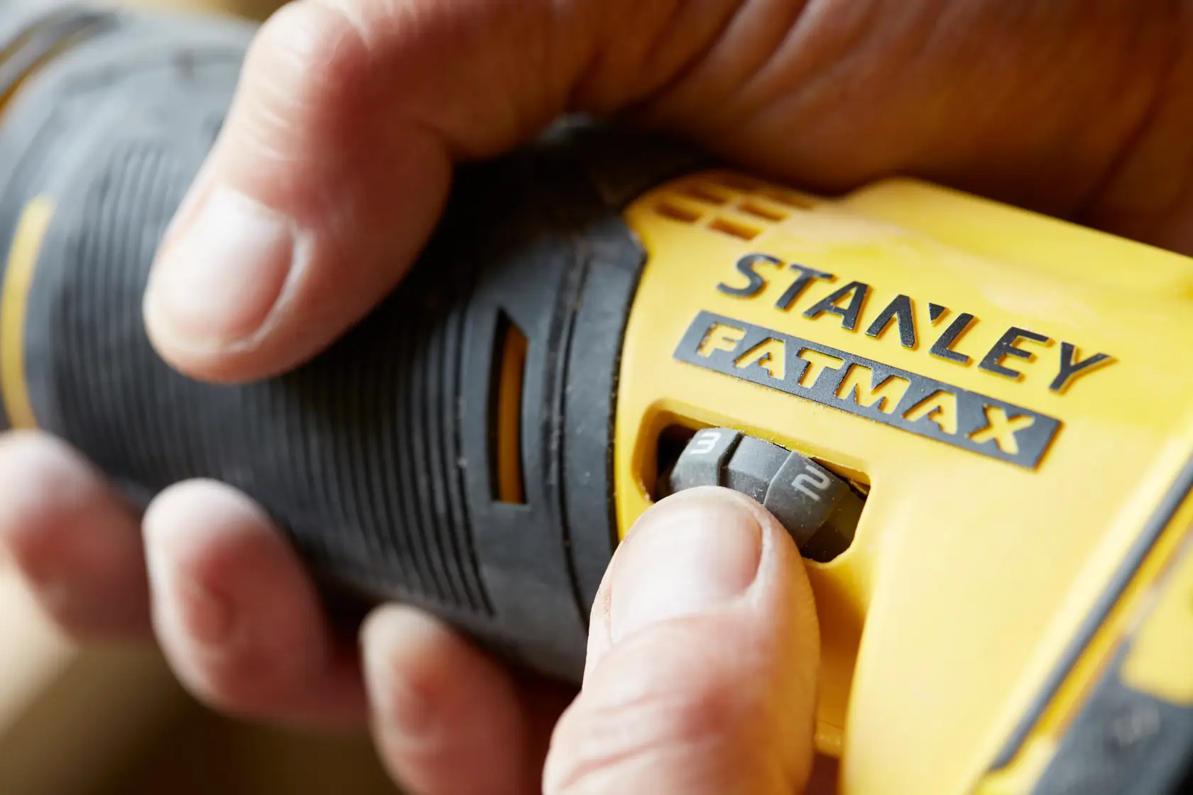 Primo piano dell’utensile STANLEY SFMCE500B FATMAX con mano che regola il selettore di velocità, fotografia di prodotto.