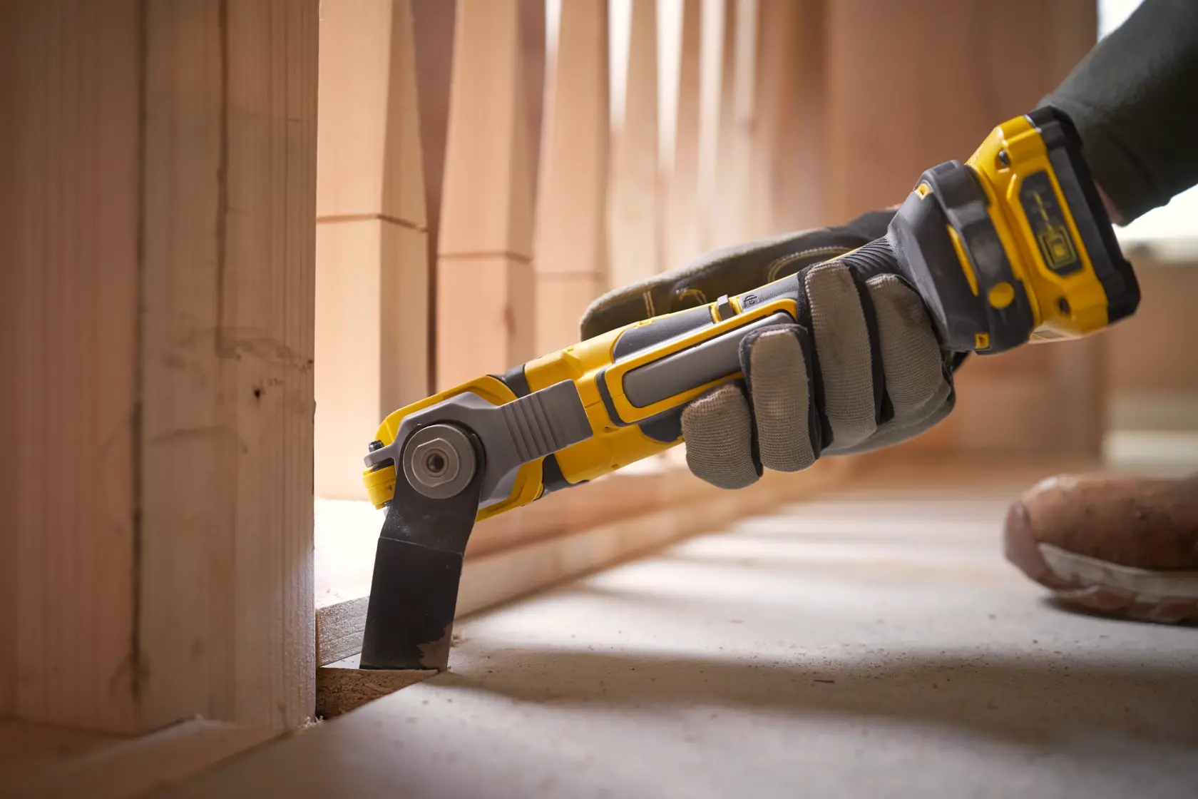 Utensile oscillante STANLEY SFMCE510B in uso, design giallo e nero, taglio del legno vicino al pavimento.