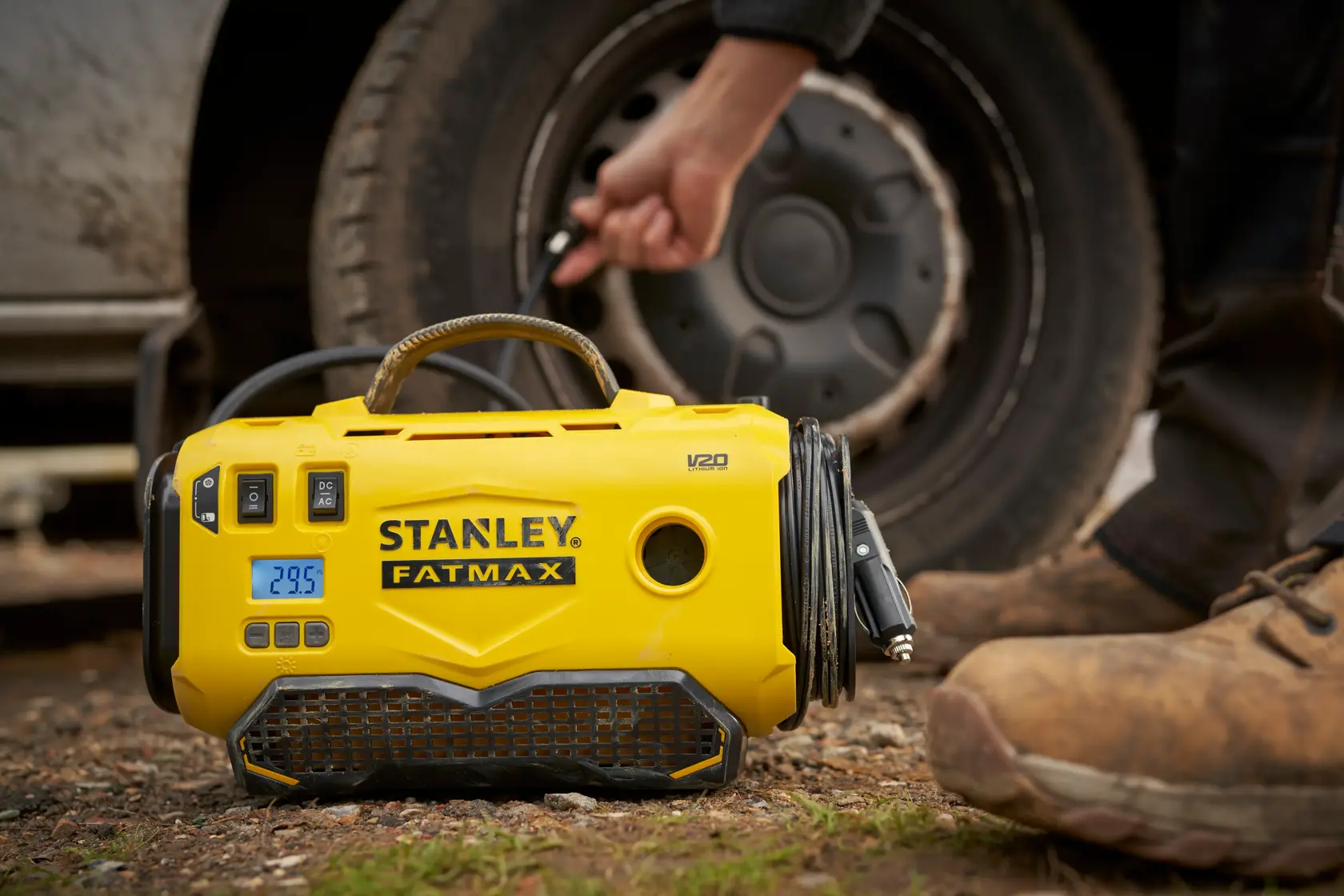 STANLEY SFMCE520B gonfiatore di pneumatici portatile giallo in uso accanto a una ruota del veicolo all'aperto.
