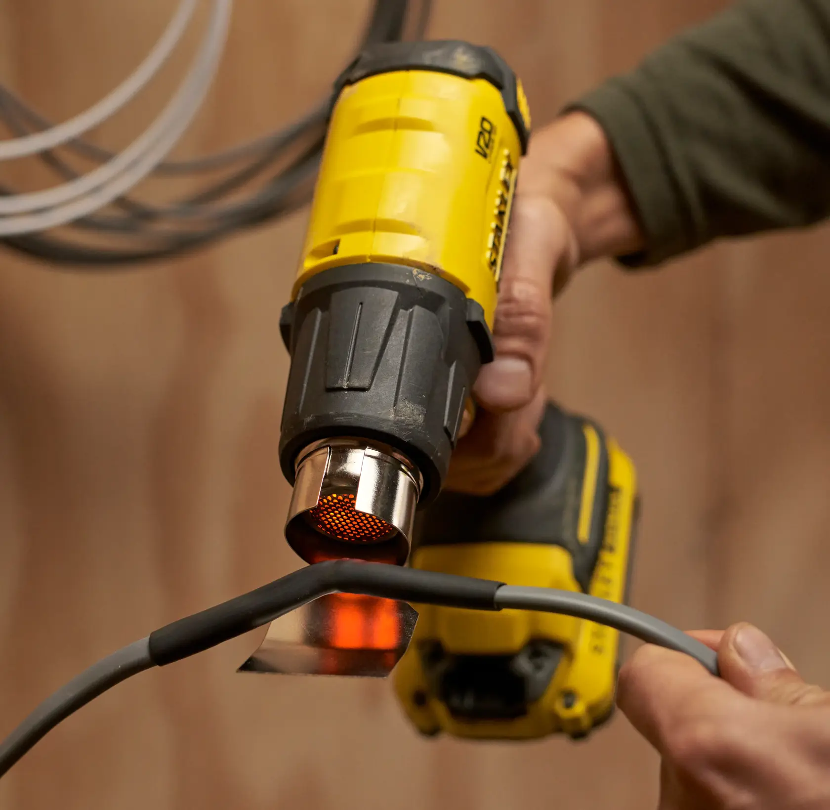 Fotografia della pistola termica cordless STANLEY SFMCE530B mentre riscalda un cavo.