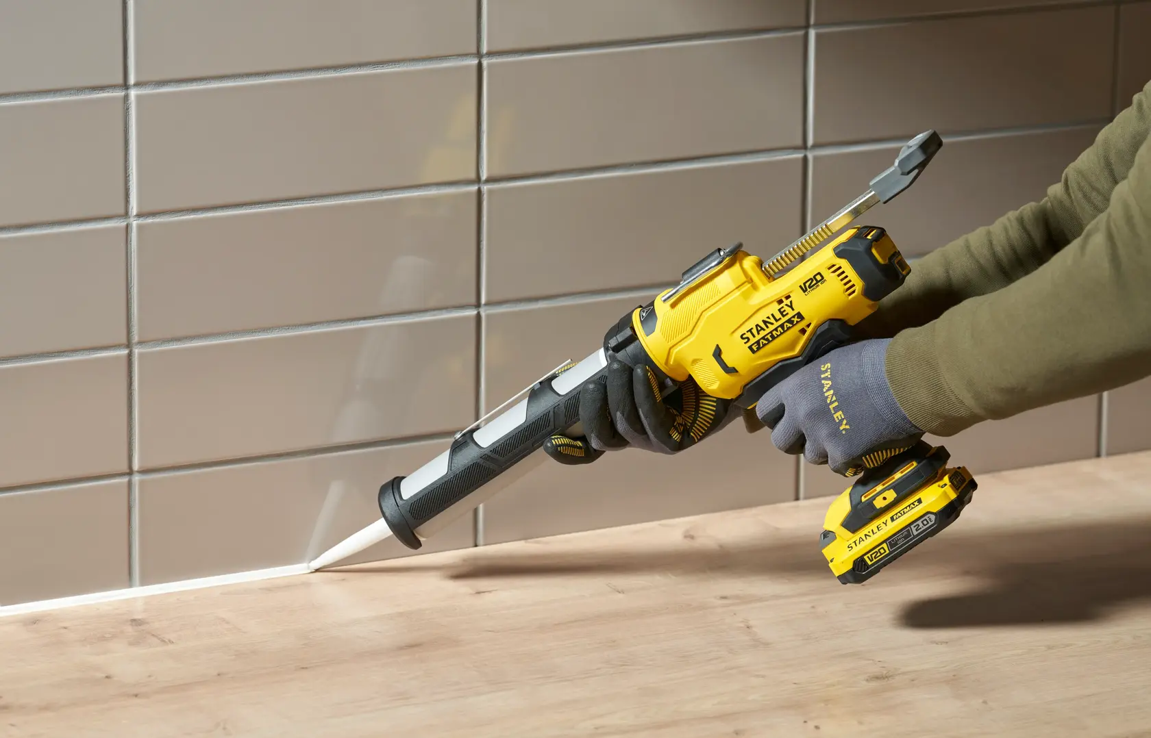 STANLEY SFMCE600B pistola per sigillare cordless in uso per sigillare una giunzione tra piano in legno e parete piastrellata.