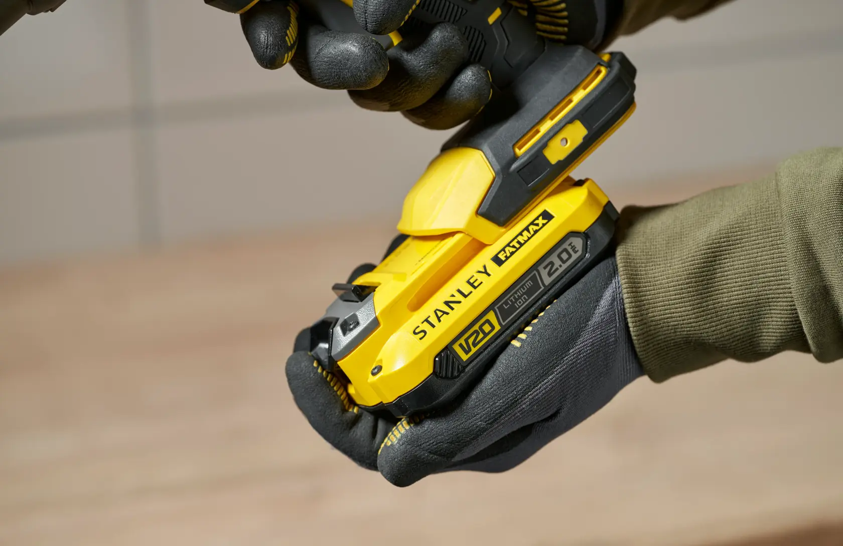 Foto dell’utensile cordless giallo STANLEY SFMCE600B tenuto con guanti, vista laterale ravvicinata.