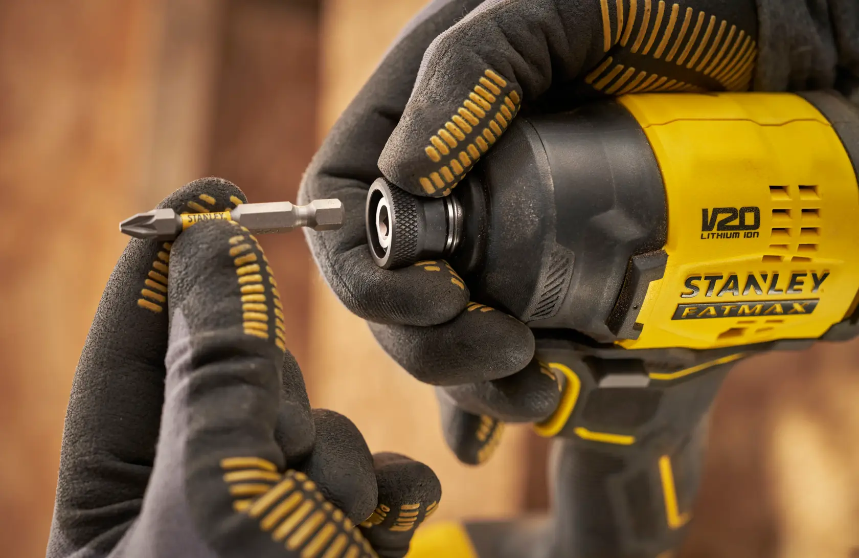 STANLEY SFMCF811D1T avvitatore a impulsi in primo piano con inserimento della punta, fotografia dello strumento con guanti.
