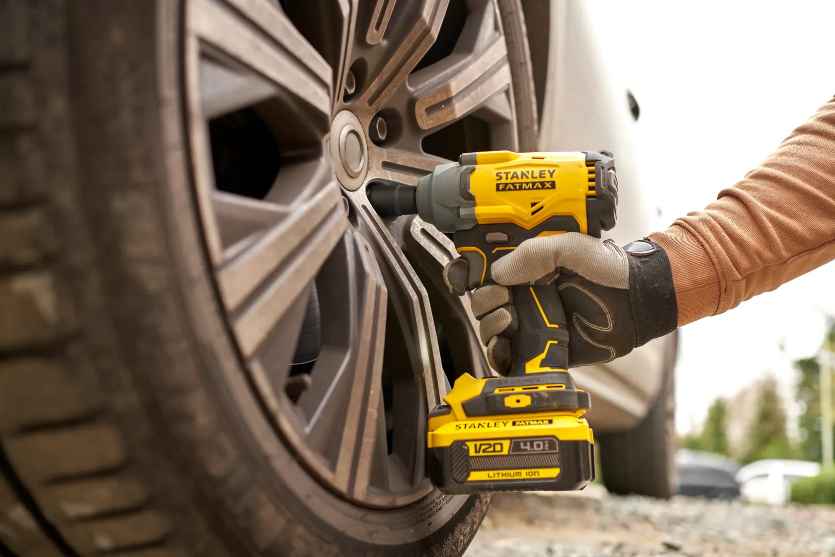Avvitatore a impulsi cordless STANLEY SFMCF920B usato su ruota d’auto, primo piano esterno.
