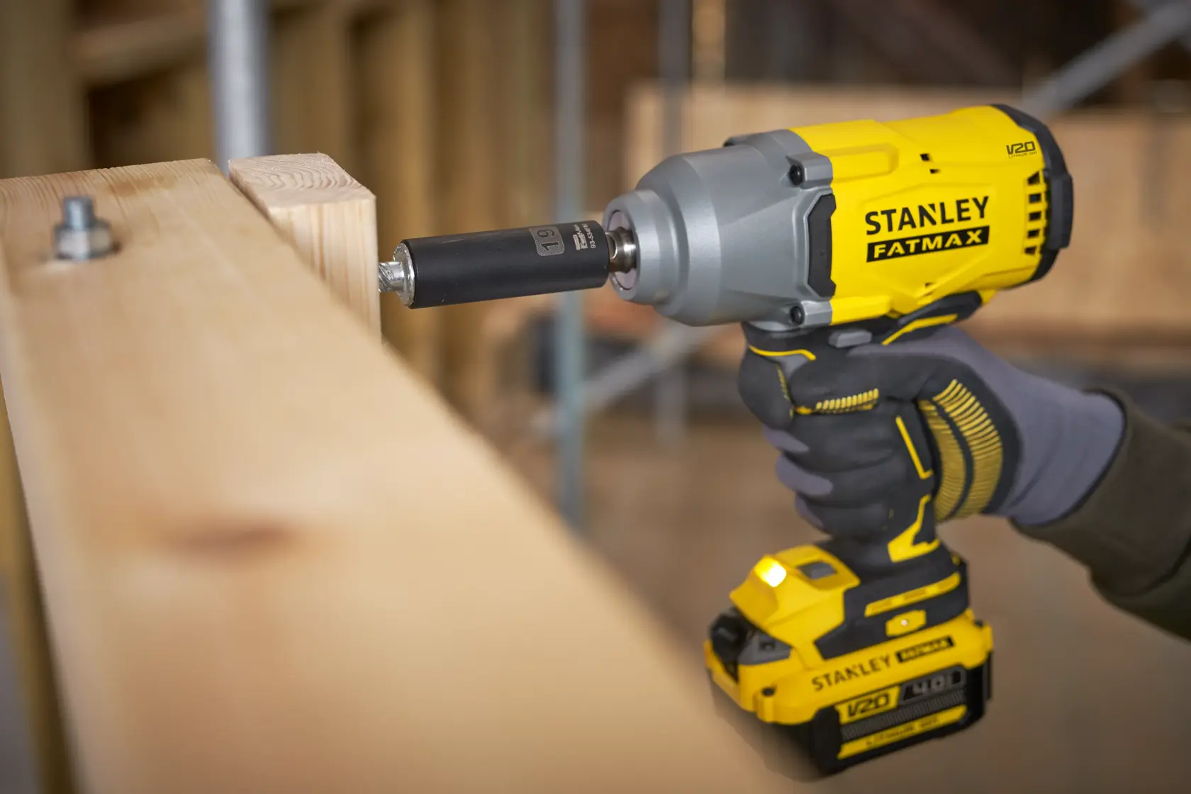 Foto dell’avvitatore a impulsi a batteria STANLEY SFMCF940B in uso su travi di legno.