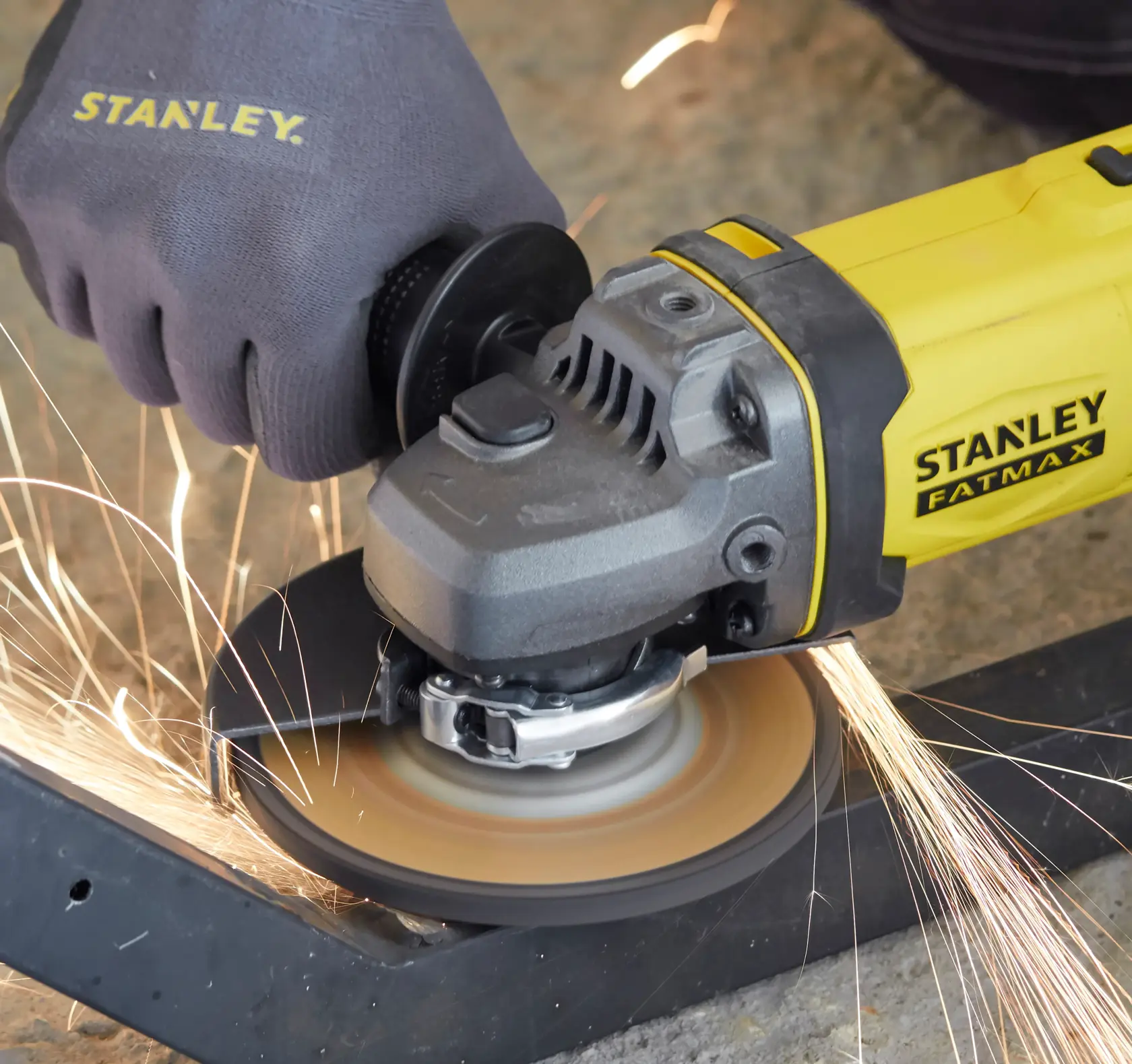 Smerigliatrice angolare STANLEY SFMCG400M2K in uso, levigando metallo con scintille, vista ravvicinata.