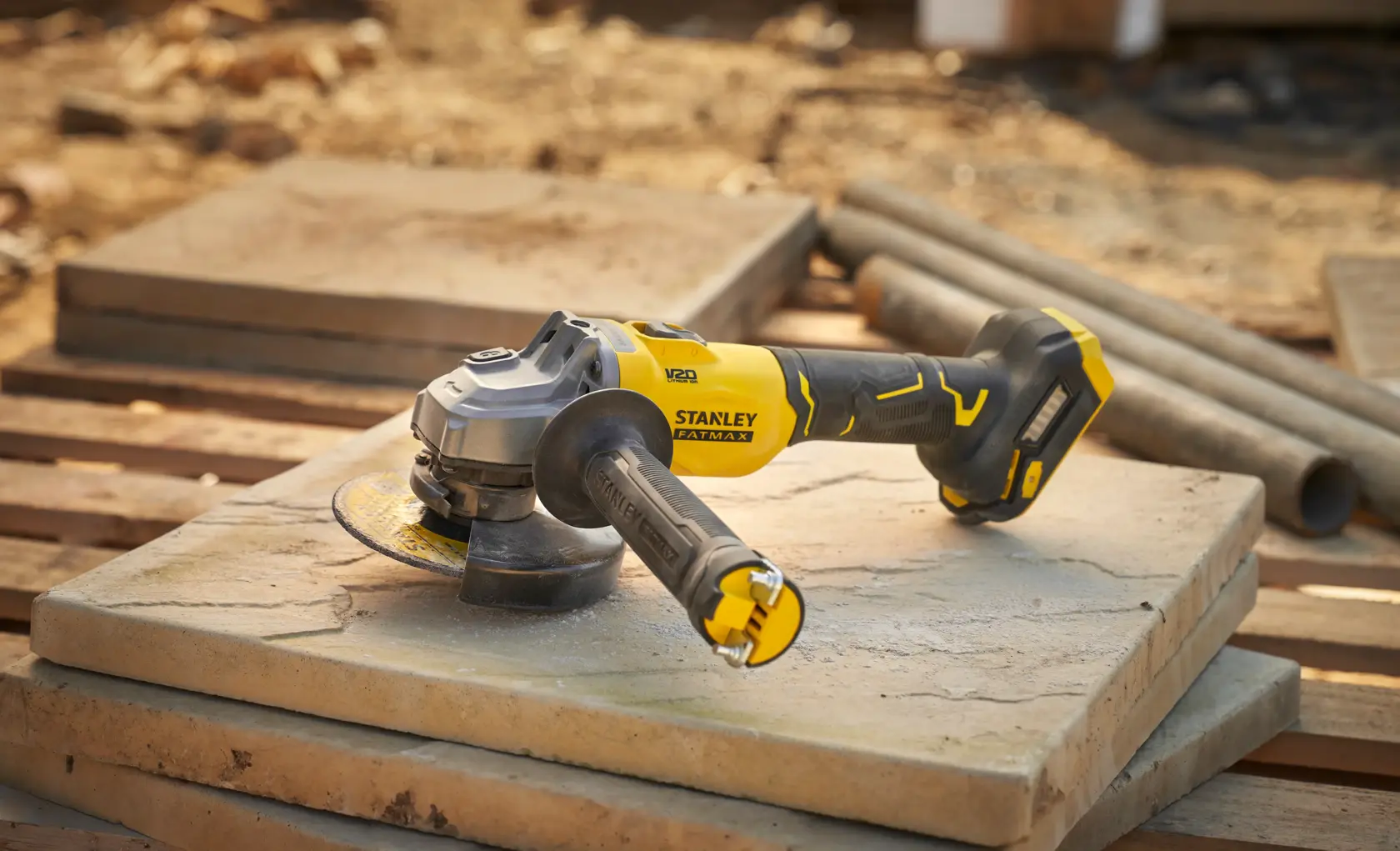 STANLEY SFMCG710B-XJ smerigliatrice angolare senza filo su lastra di pietra, gialla e nera, foto all’aperto.