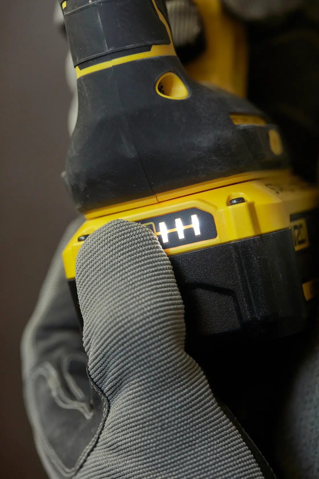 STANLEY SFMCH900B utensile elettrico in primo piano, indicatore batteria acceso, guanto preme pulsante, vista laterale.