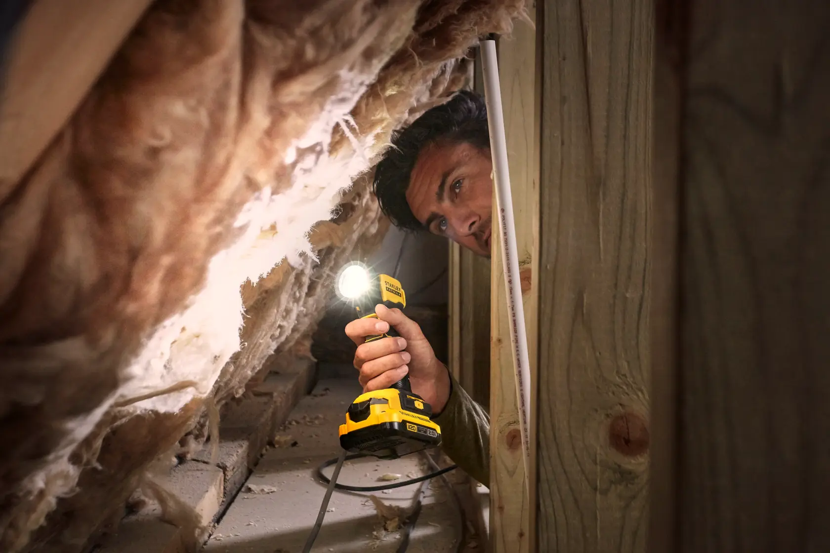 STANLEY SFMCL020B lampada da lavoro cordless usata in una soffitta, corpo giallo illumina l'isolamento.