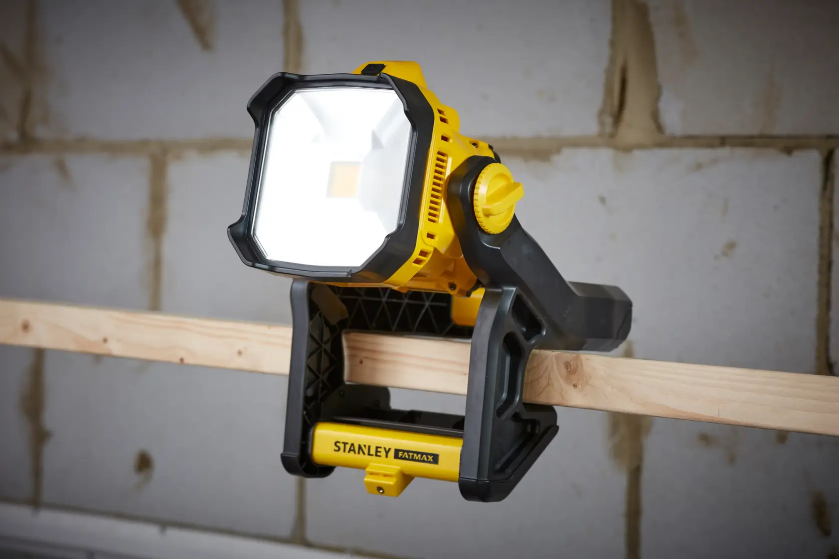 STANLEY SFMCL030B luce da lavoro LED gialla e nera fissata a una trave di legno, angolo frontale.