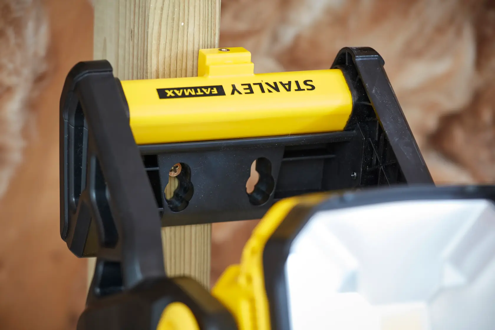 STANLEY SFMCL030B luce da lavoro montata su palo di legno, vista ravvicinata, corpo giallo e nero.