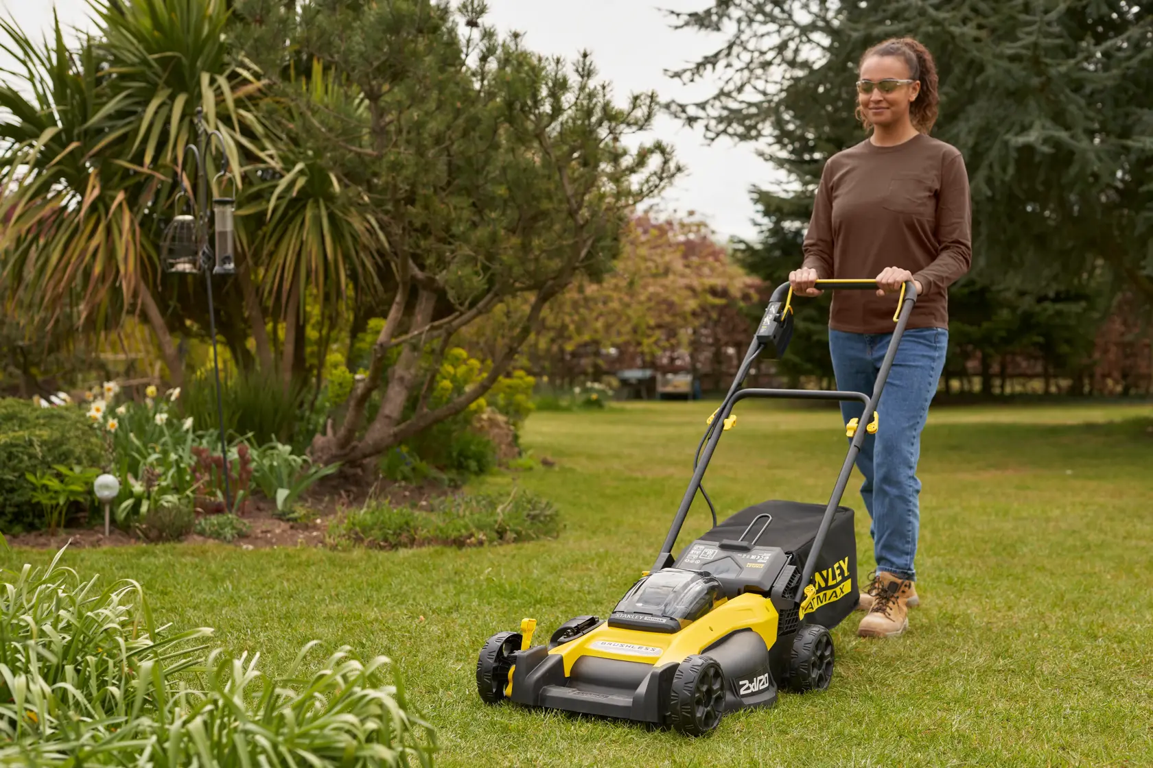 Foto del tagliaerba STANLEY SFMCMW2651M in uso sull’erba, design giallo e nero, sfondo giardino.