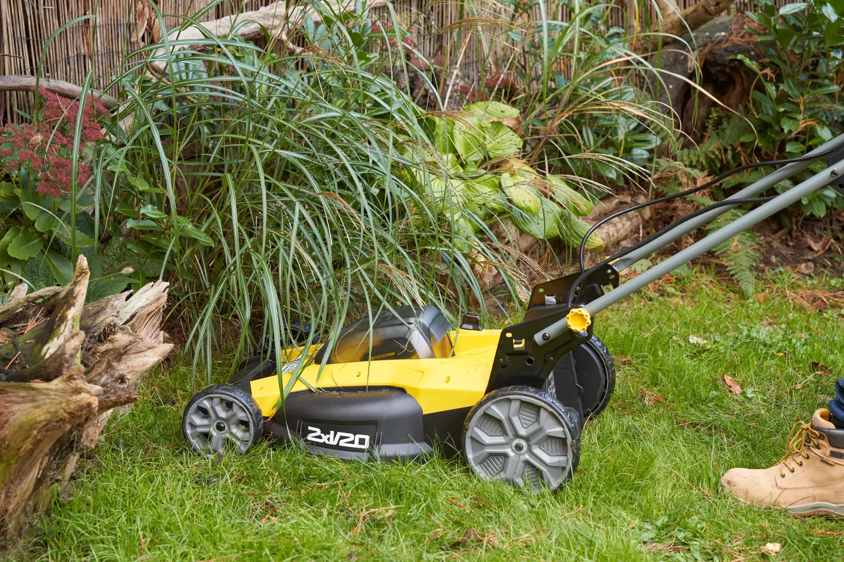 STANLEY SFMCMWS251M tosaerba vista laterale taglia erba vicino a piante all’aperto.