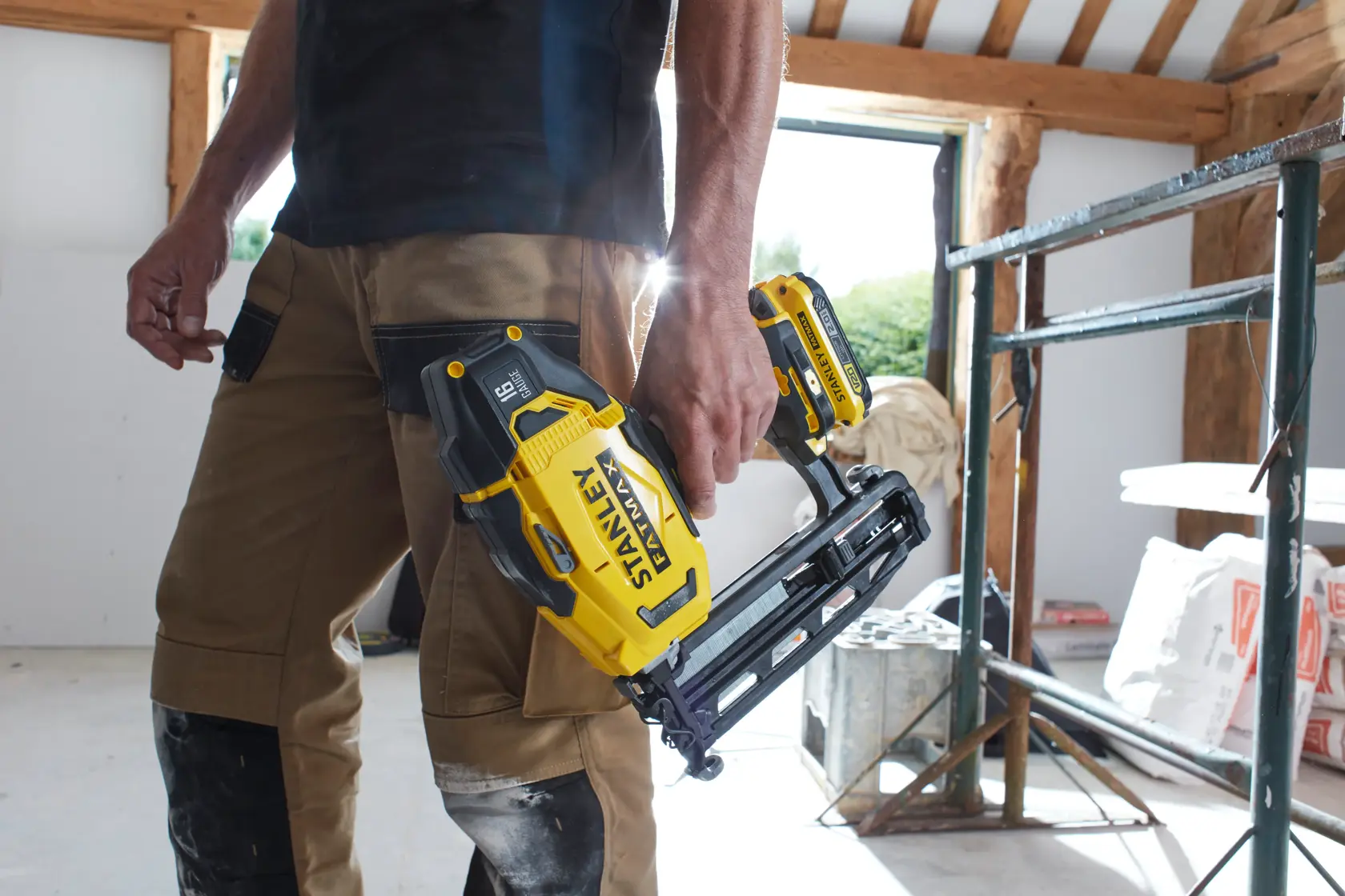 Chiodatrice a batteria STANLEY SFMCN616D2K tenuta da persona con pantaloni da lavoro in cantiere.