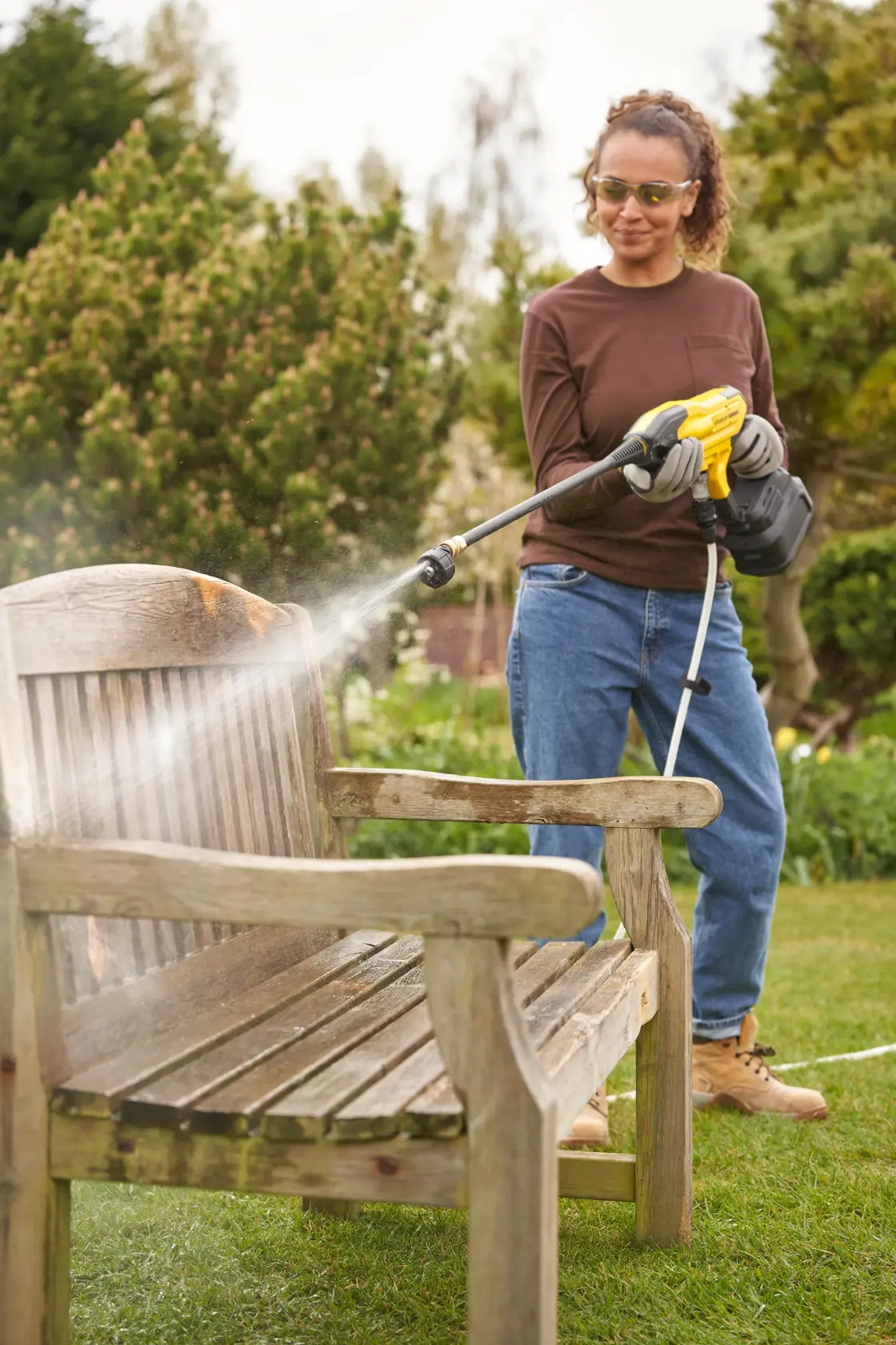 STANLEY SFMCPC93B pulitore ad alta pressione spruzza acqua su panchina di legno in giardino.