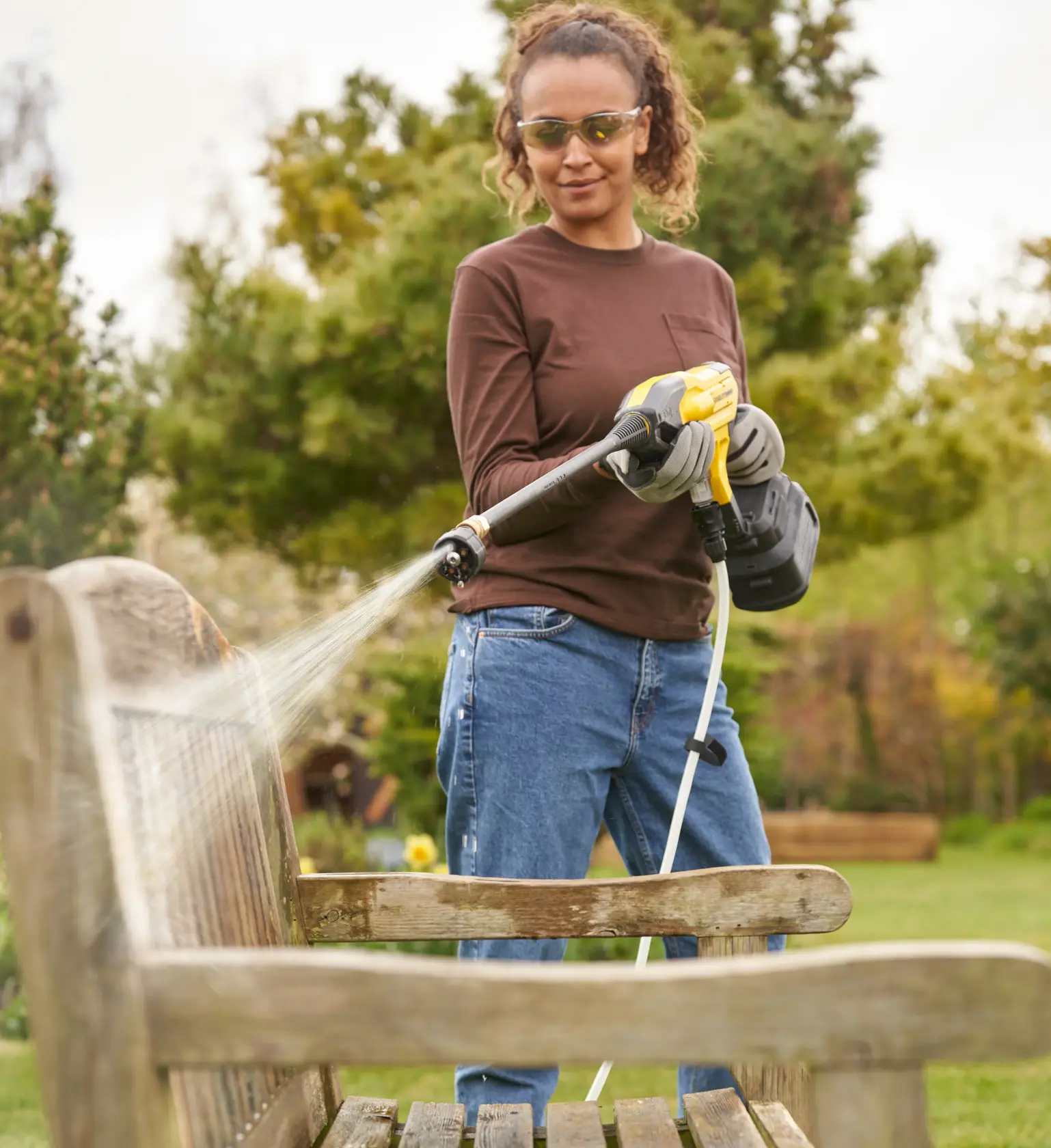 STANLEY SFMCPC93M1 pulitore ad alta pressione portatile che spruzza acqua su una panchina di legno all'aperto.