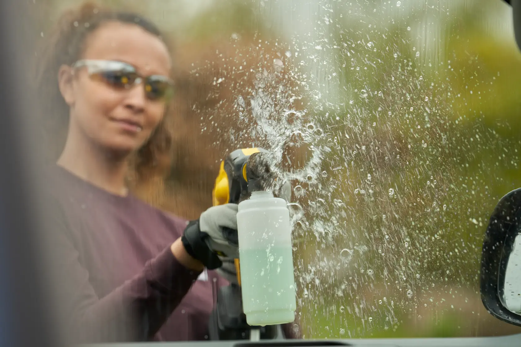 Foto dello strumento per la pulizia STANLEY SFMCPC93M1 che spruzza liquido su un finestrino auto.